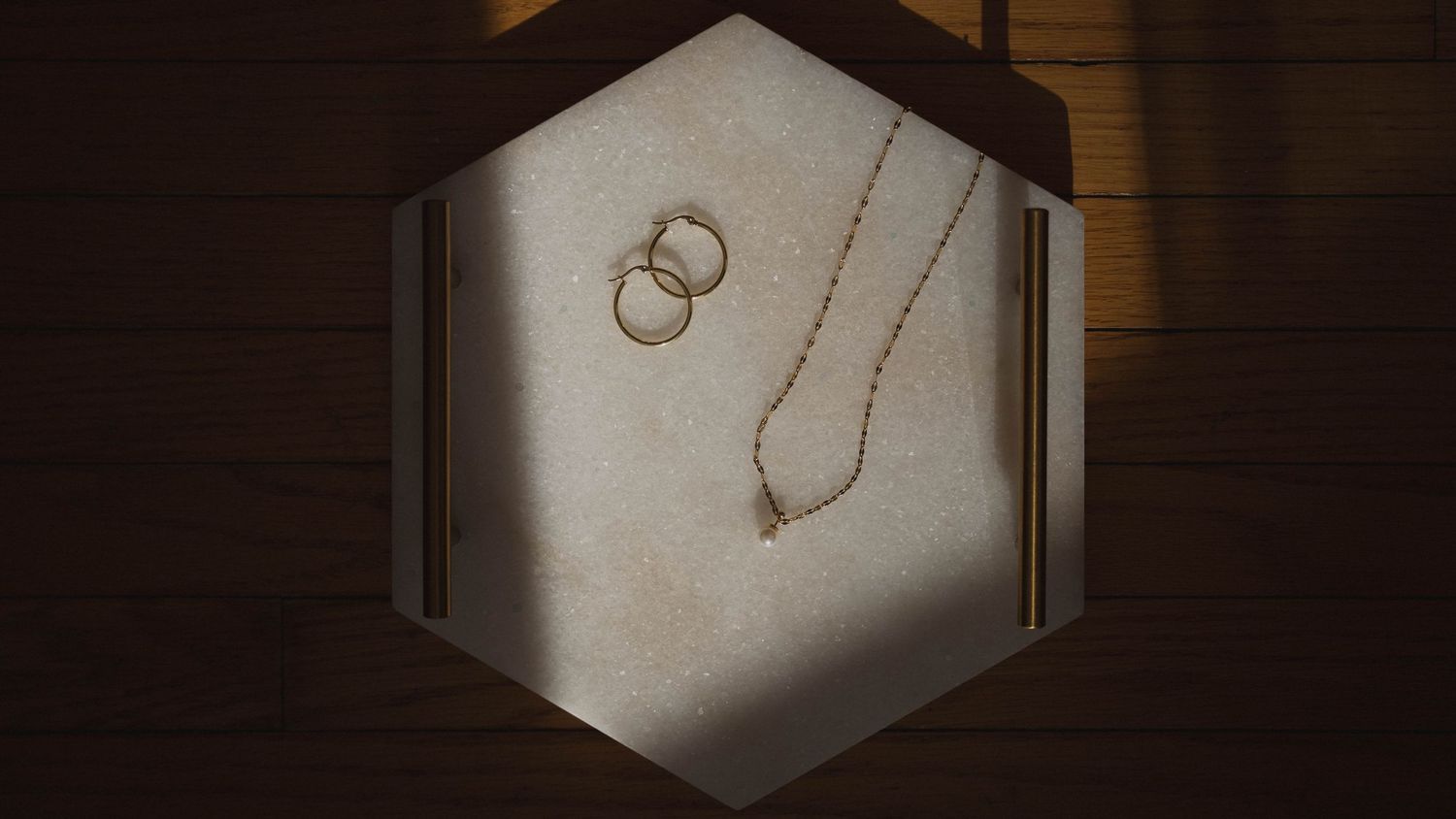 Minimalist jewelry display with rings and chains on white background in dramatic lighting.