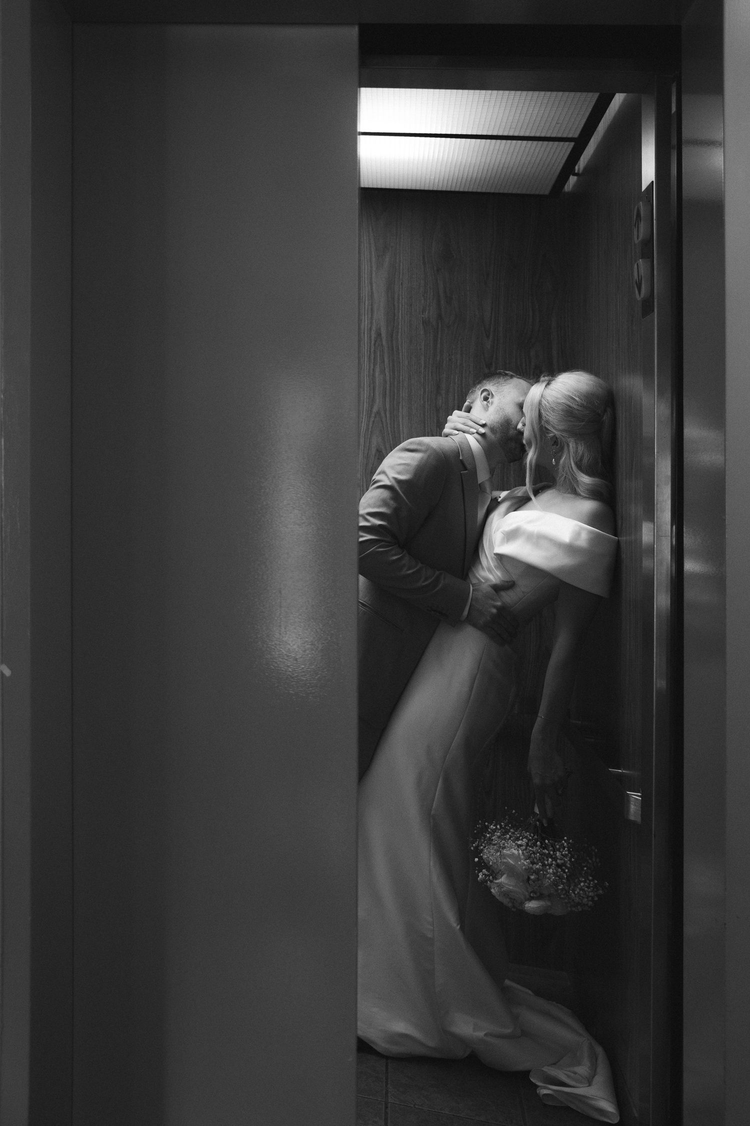 A romantic black and white photo of a couple embracing in an elevator.
