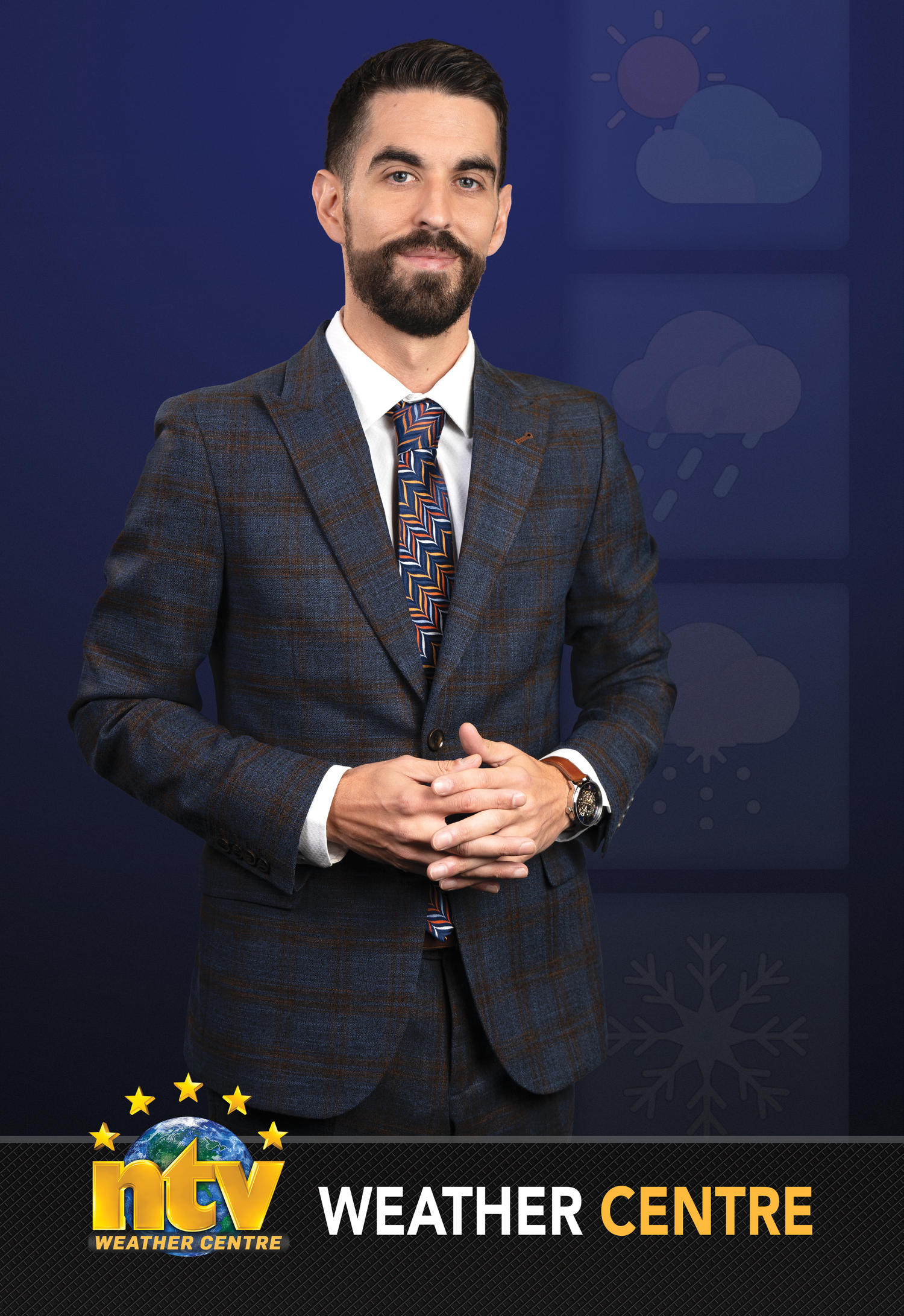 Male weather presenter in plaid suit with patterned tie stands before NTV Weather Centre backdrop with weather icons.