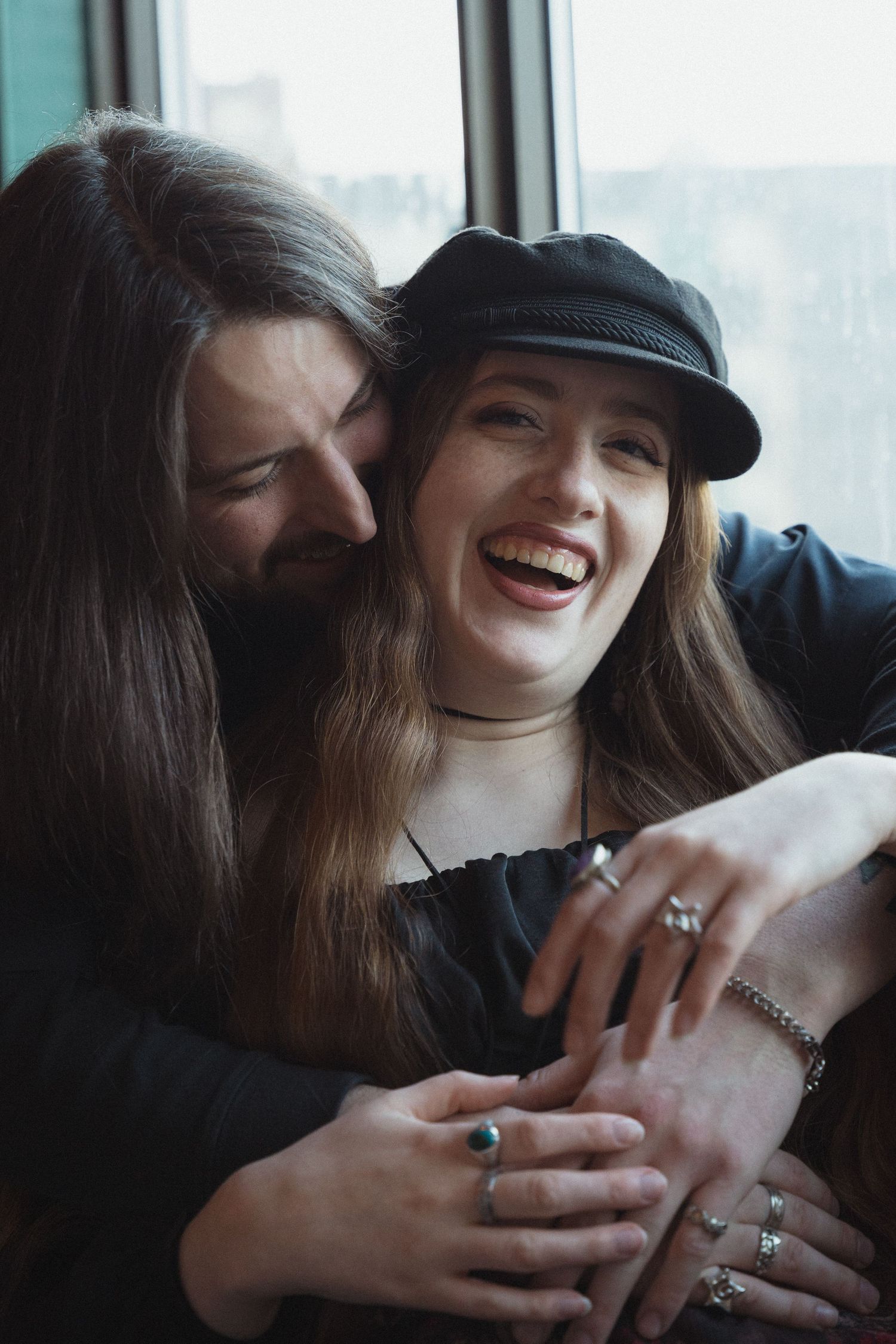 Close up of hands showing off engagement rings with joyful expressions.
