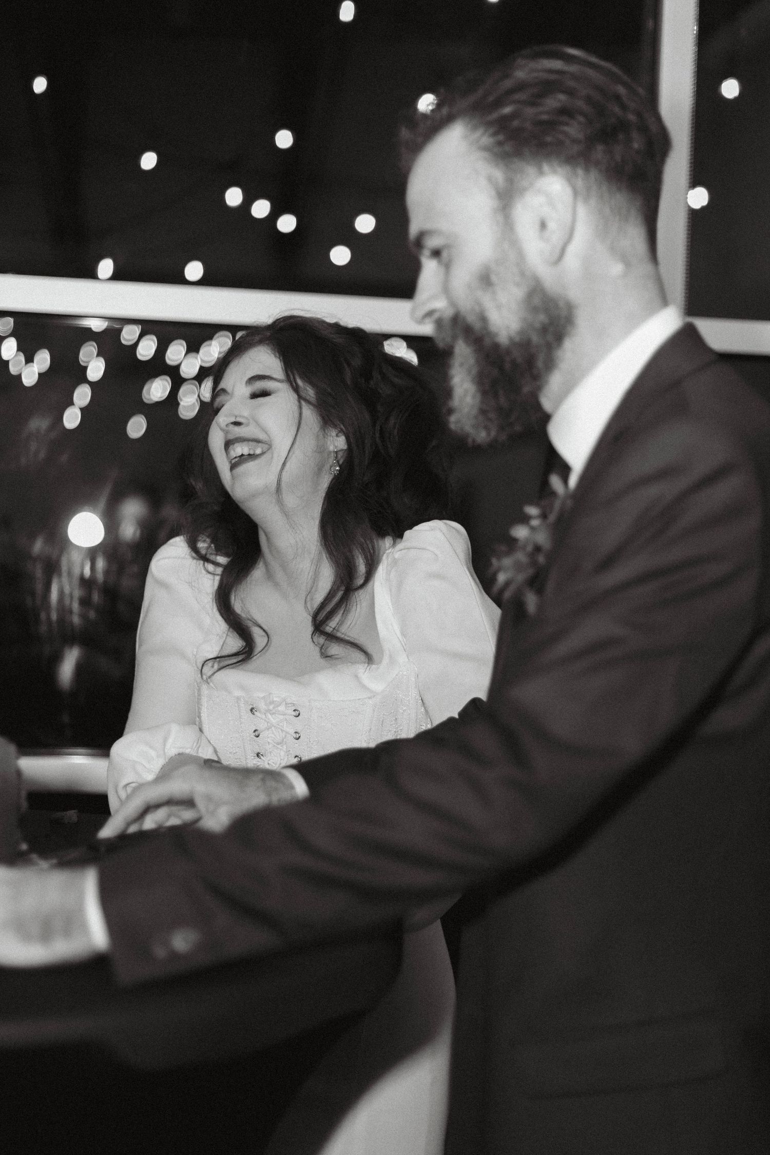 A couple shares an intimate dance moment under twinkling string lights at an evening reception.