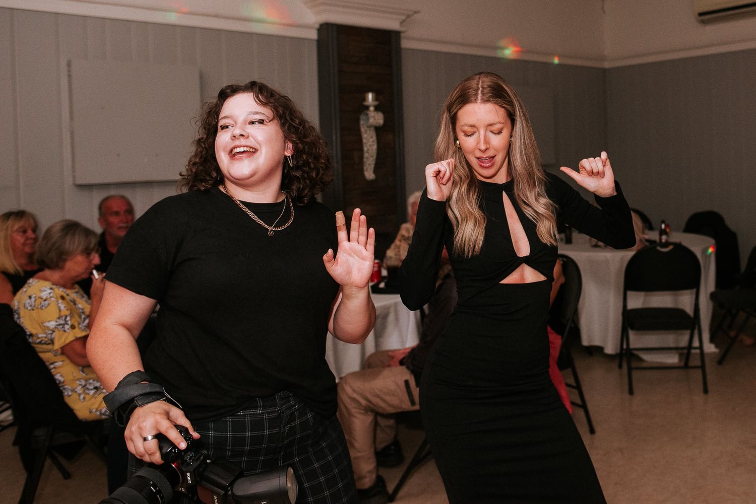 Two people dancing and laughing at an indoor event.