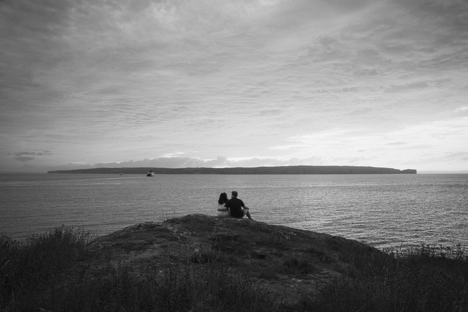 Dramatic black and white landscape with cloudy sky over rolling hills.