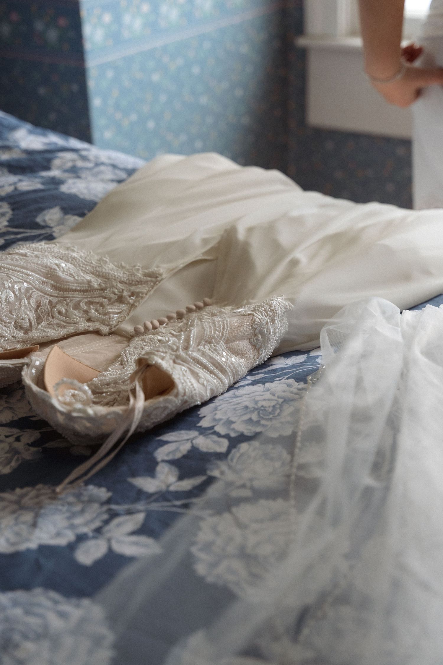 Close-up view of delicate white lace fabric with intricate floral patterns laid on a blue surface.