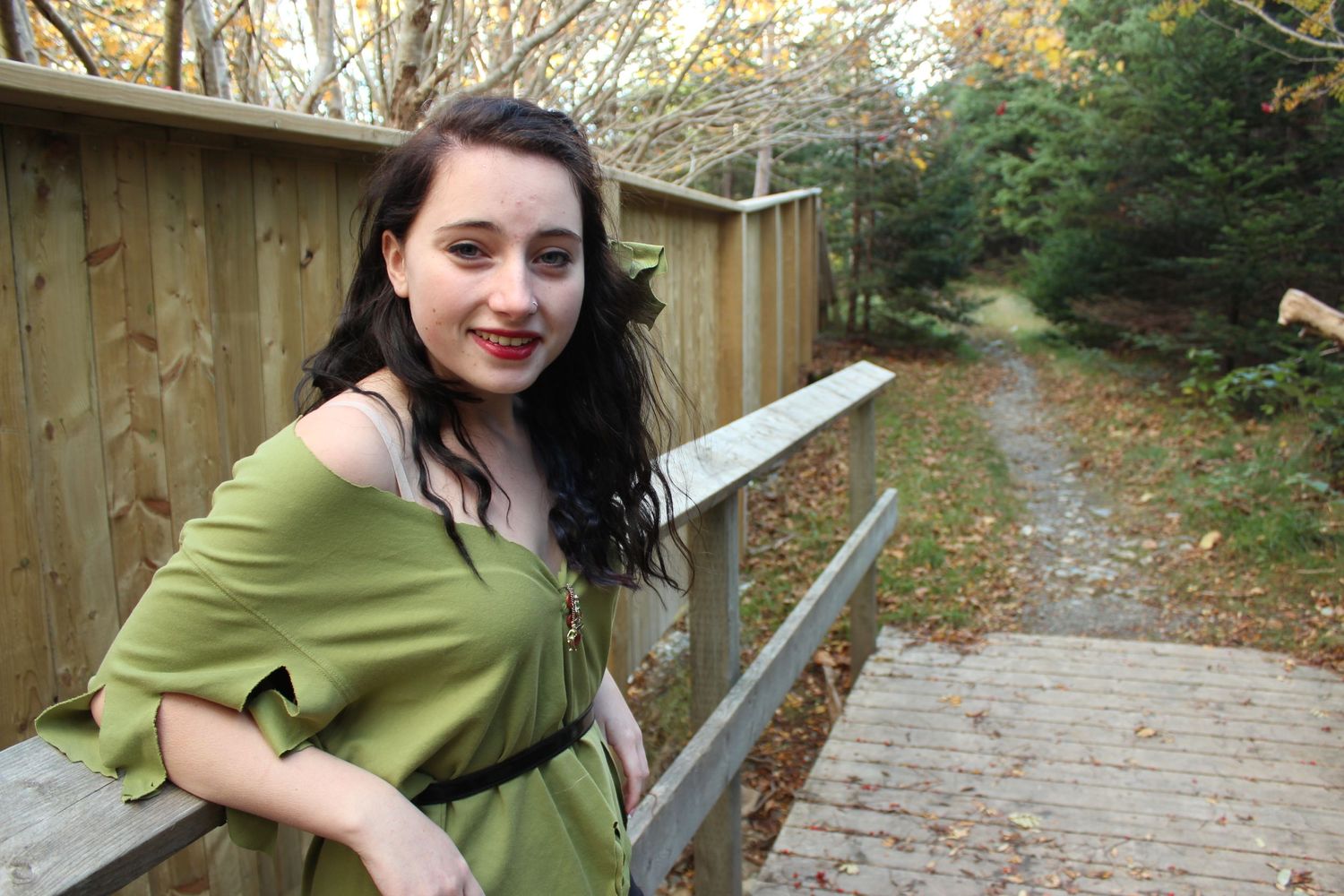 Figure walks along a wooden boardwalk path through autumn trees.