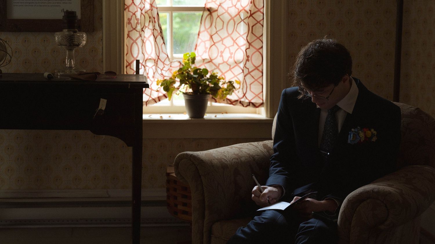 Wedding couple shares a tender moment in a dimly lit room with ornate window patterns.