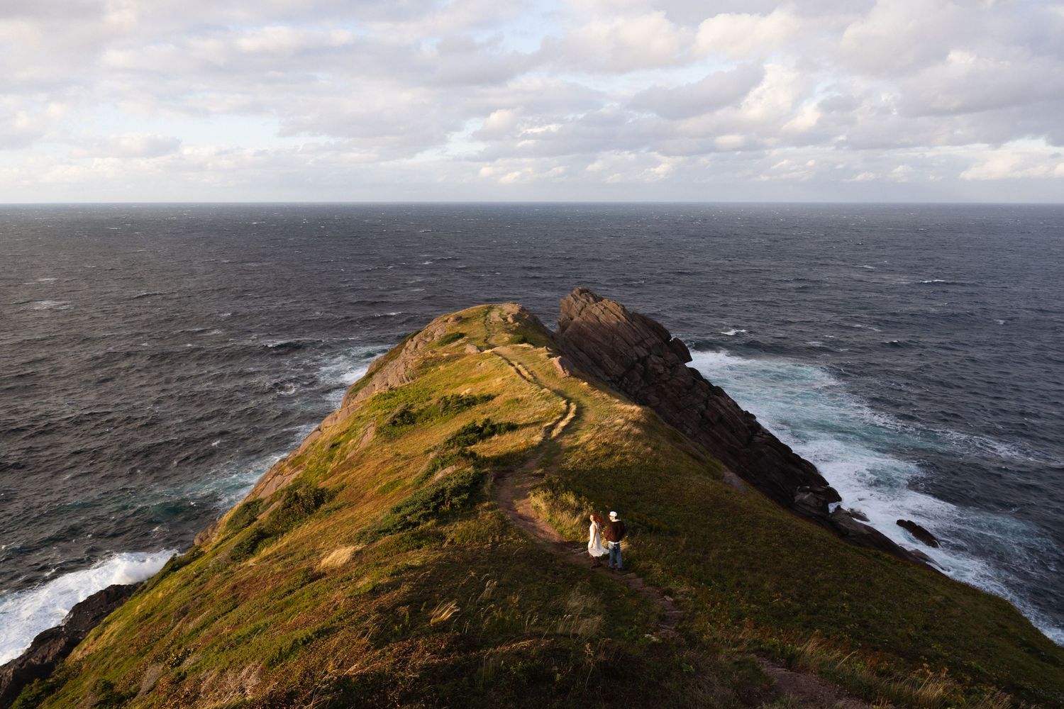Dramatic aerial view of rugged coastline with waves crashing against rocky cliffs.