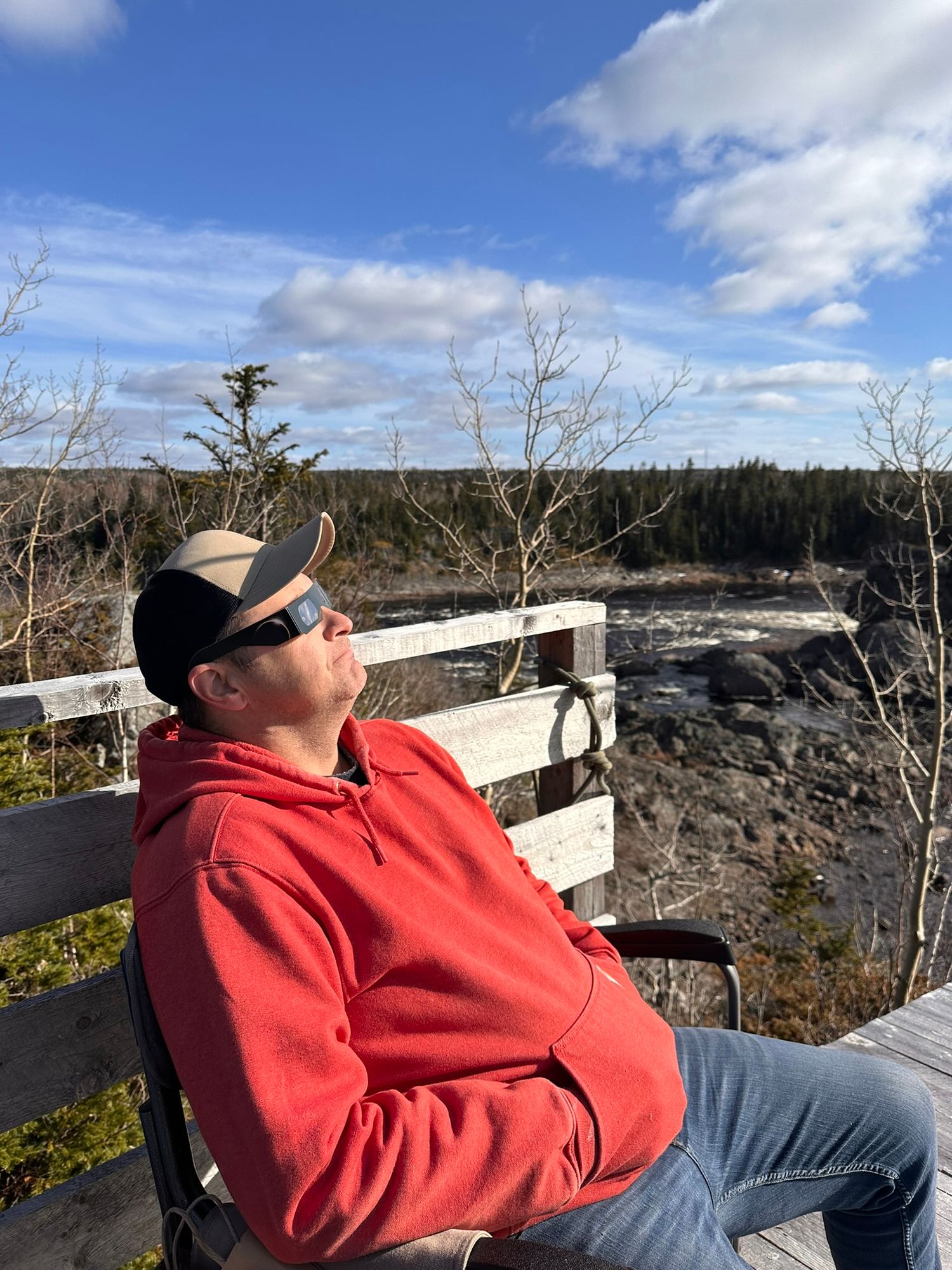 Person in red jacket photographing from an elevated observation deck in winter landscape.