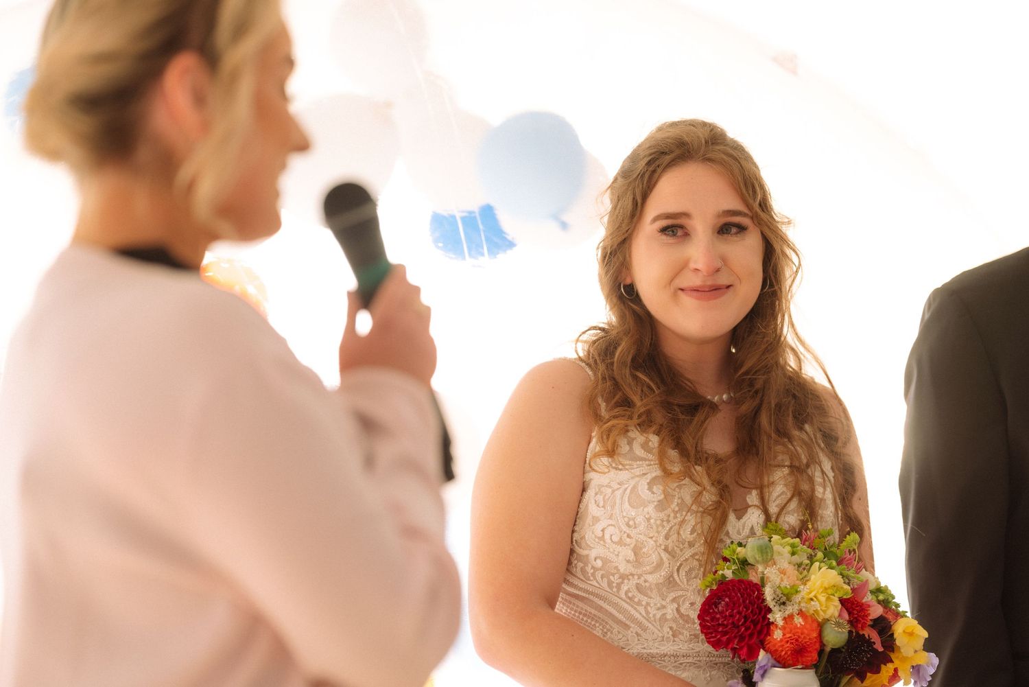 A wedding party gathers outdoors with colorful flowers and formal attire.