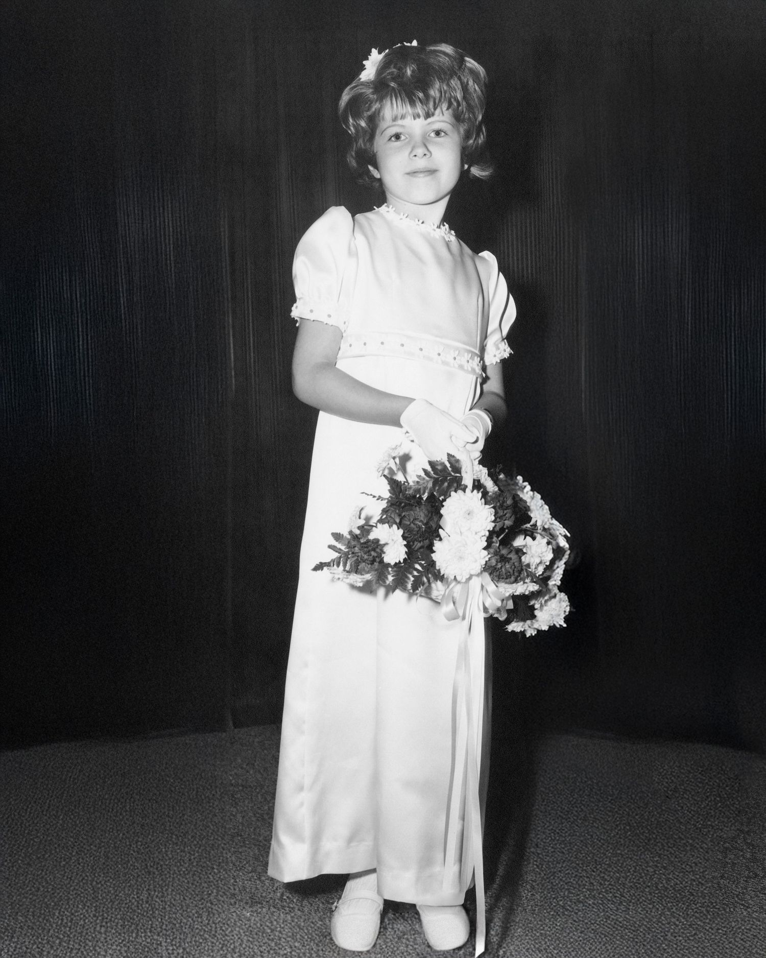 A black and white photograph of a child holding flowers in a vintage style.
