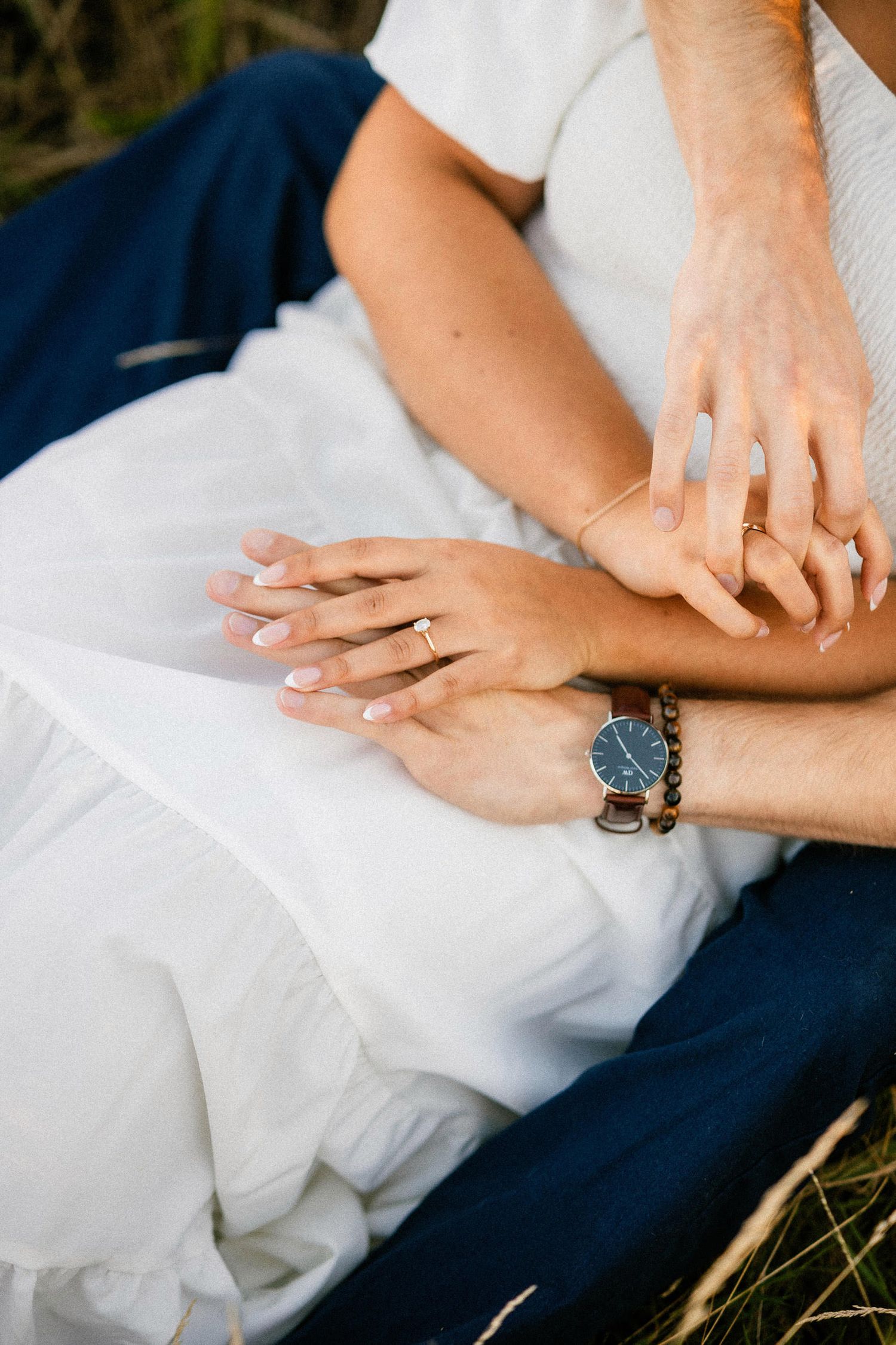 A series of wedding ring detail shots showing hands clasped together against white and navy blue fabric.