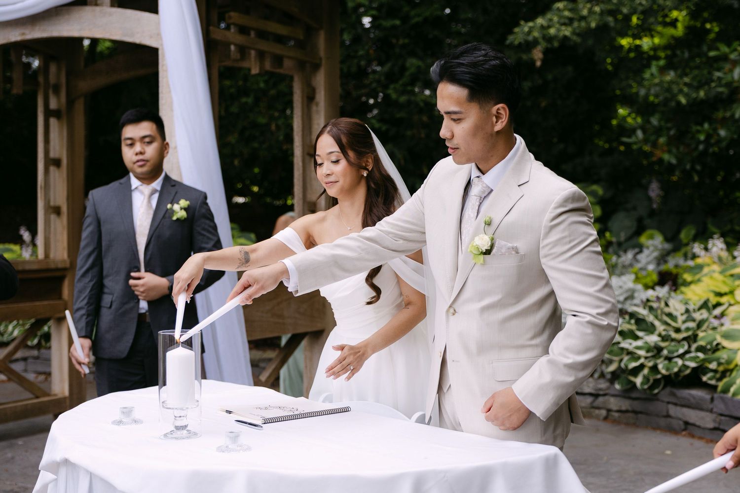 Bride and groom perform a unity sand ceremony at an outdoor garden wedding reception.