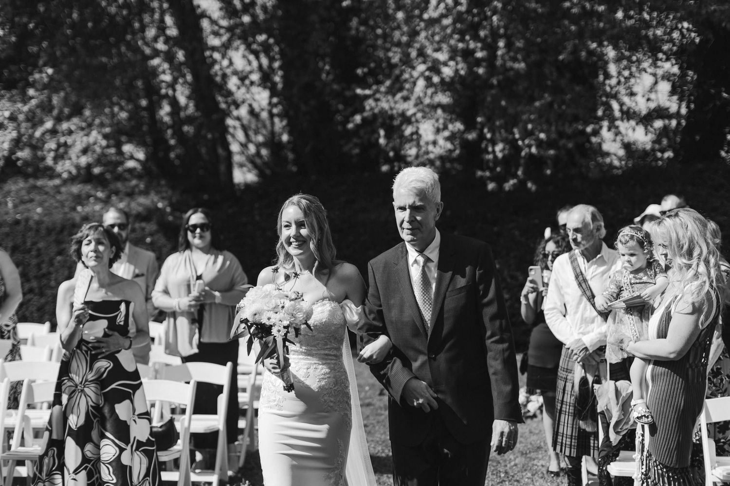 A series of candid black and white photos showing guests enjoying an outdoor wedding celebration in a garden setting.