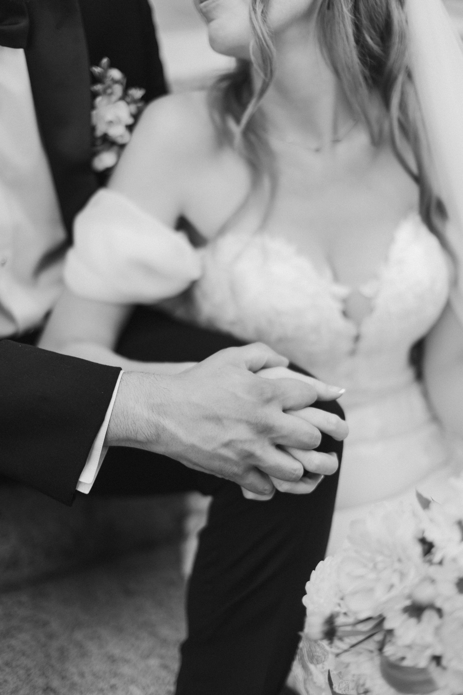 A black and white wedding photo series showing close-up details of a couple's hands during their ceremony.