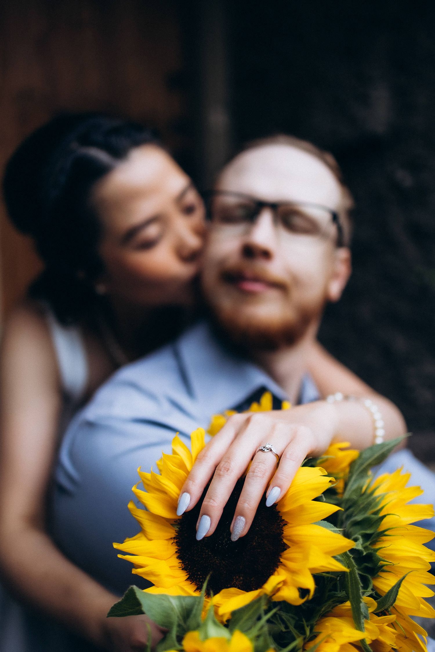 A close-up series of intimate photos showing someone holding bright yellow sunflowers against a dark background.