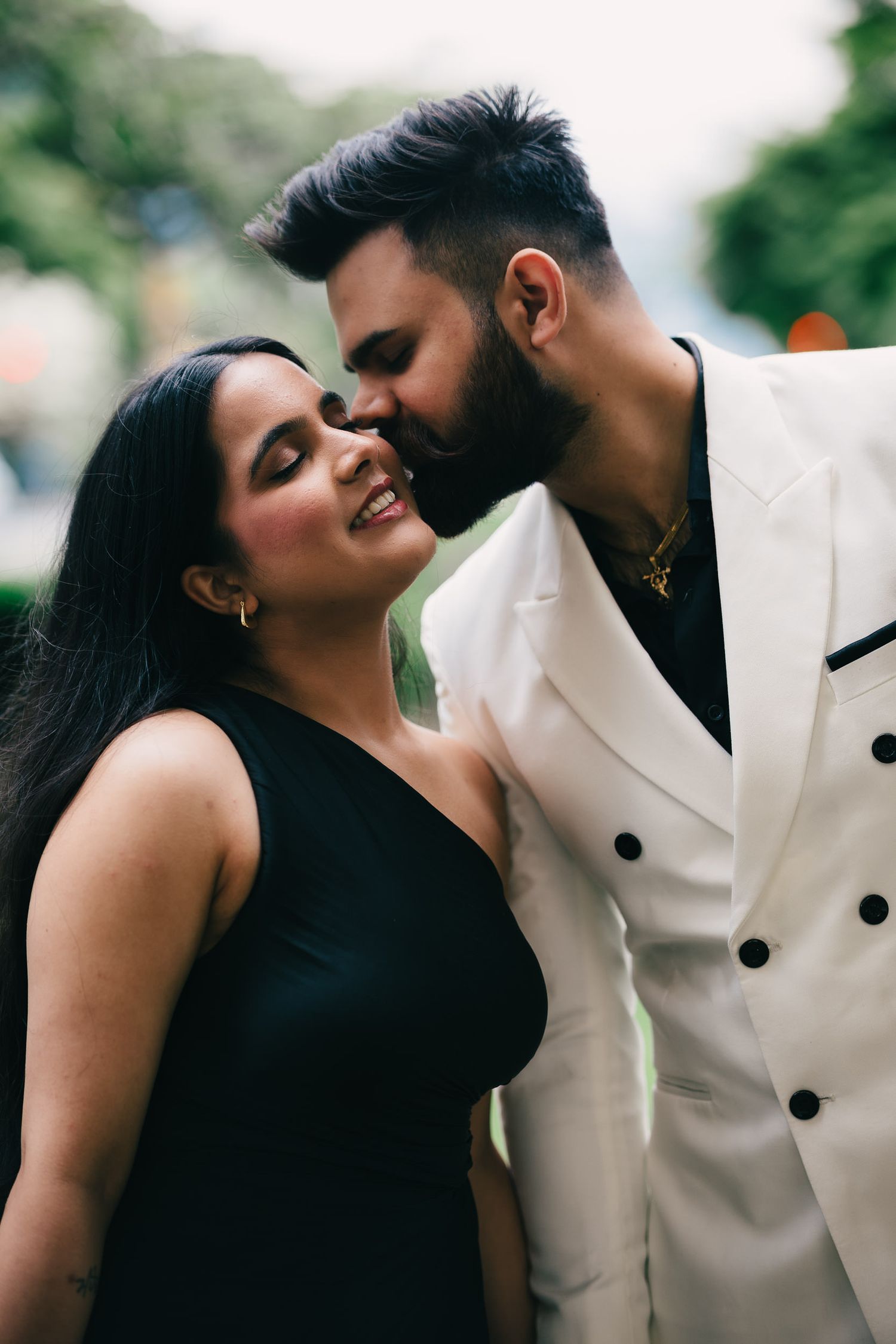 A romantic couple in contrasting black and white outfits share intimate moments in a series of close-up portraits.