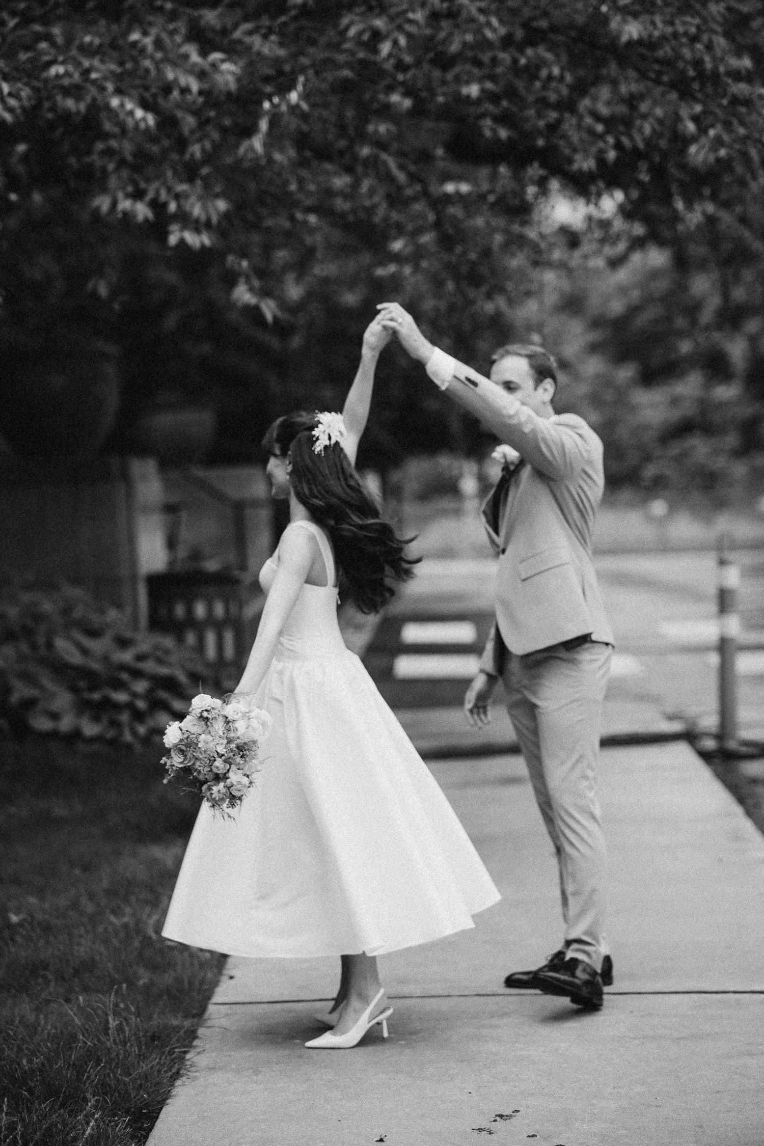 Black and white sequence of a couple dancing together in a romantic outdoor setting, with the bride's dress twirling elegantly.