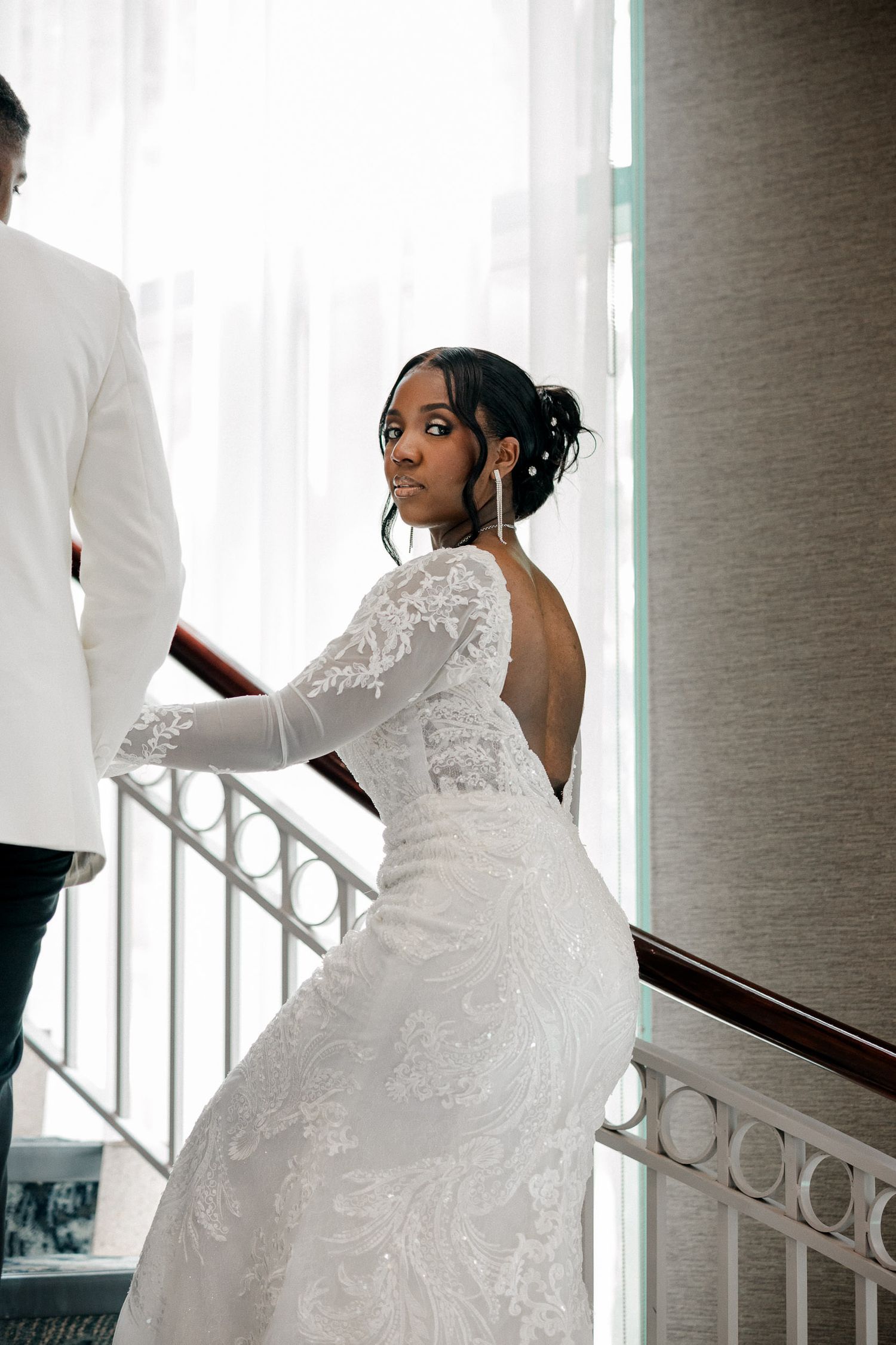 A sequence of photos showing a bride in a lace wedding gown ascending a staircase in dramatic lighting.
