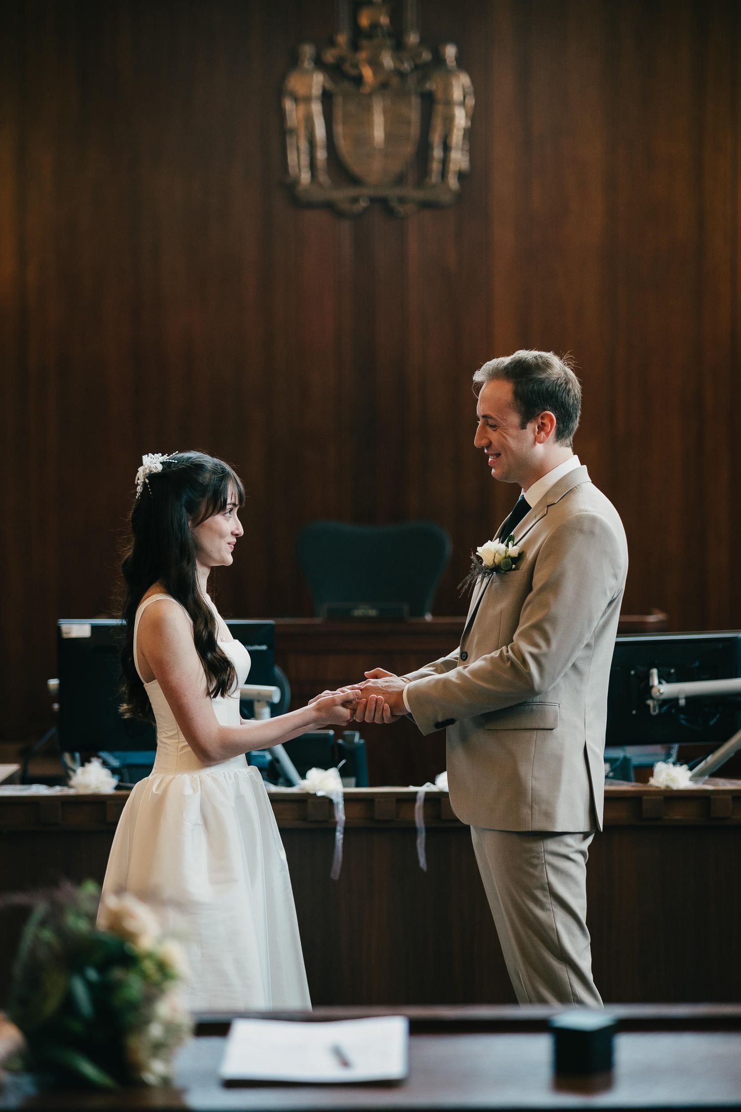 A couple shares a romantic first dance at their wedding reception in a wood-paneled venue.