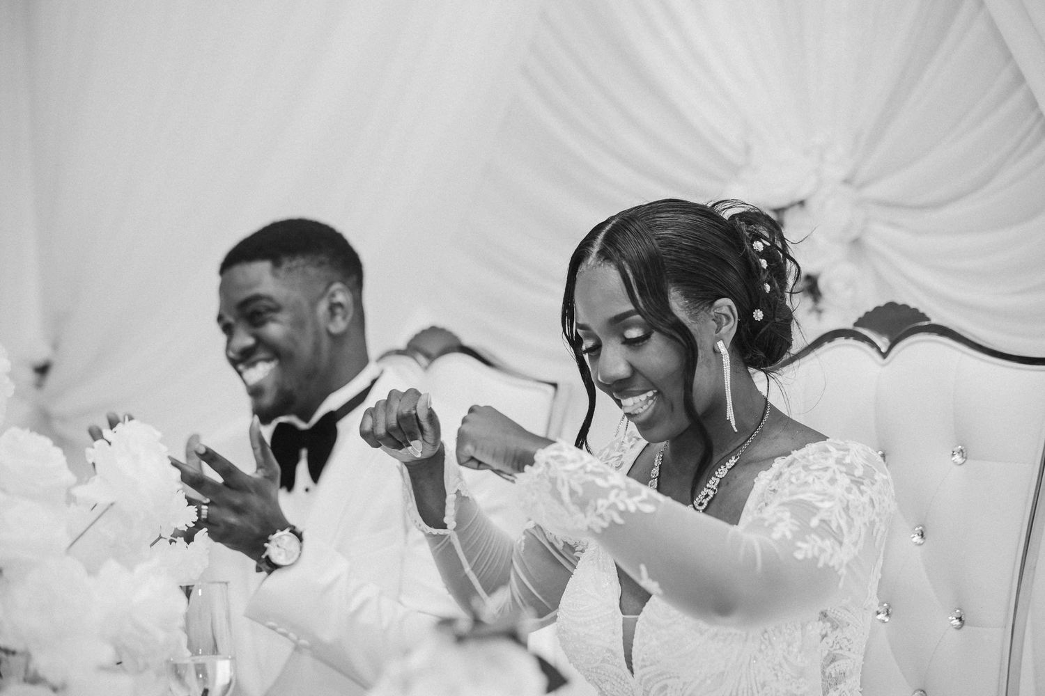 Wedding party celebrates joyfully in black and white candid moments during reception.