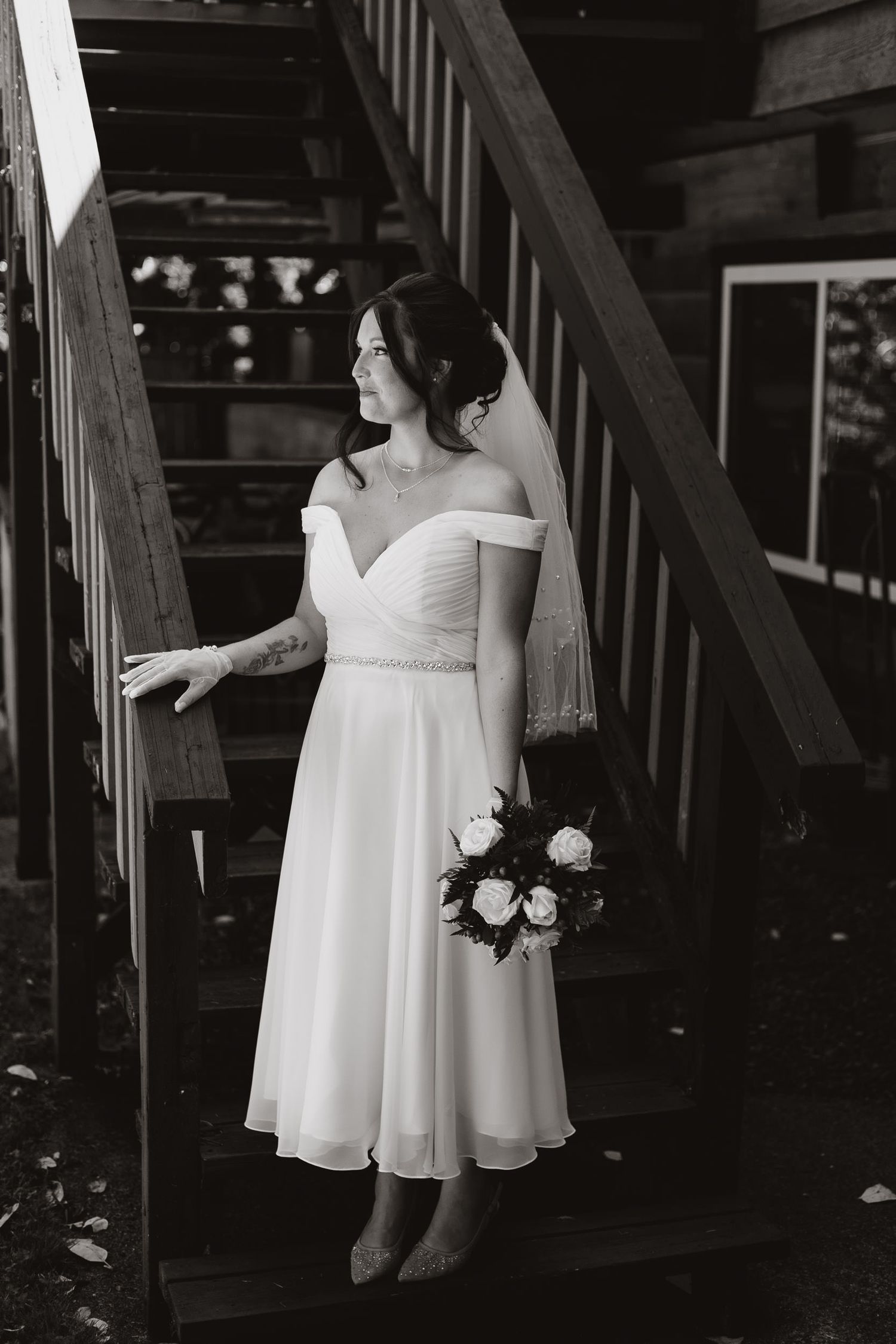 Black and white photo of bridesmaids in white dresses standing on wooden stairs.