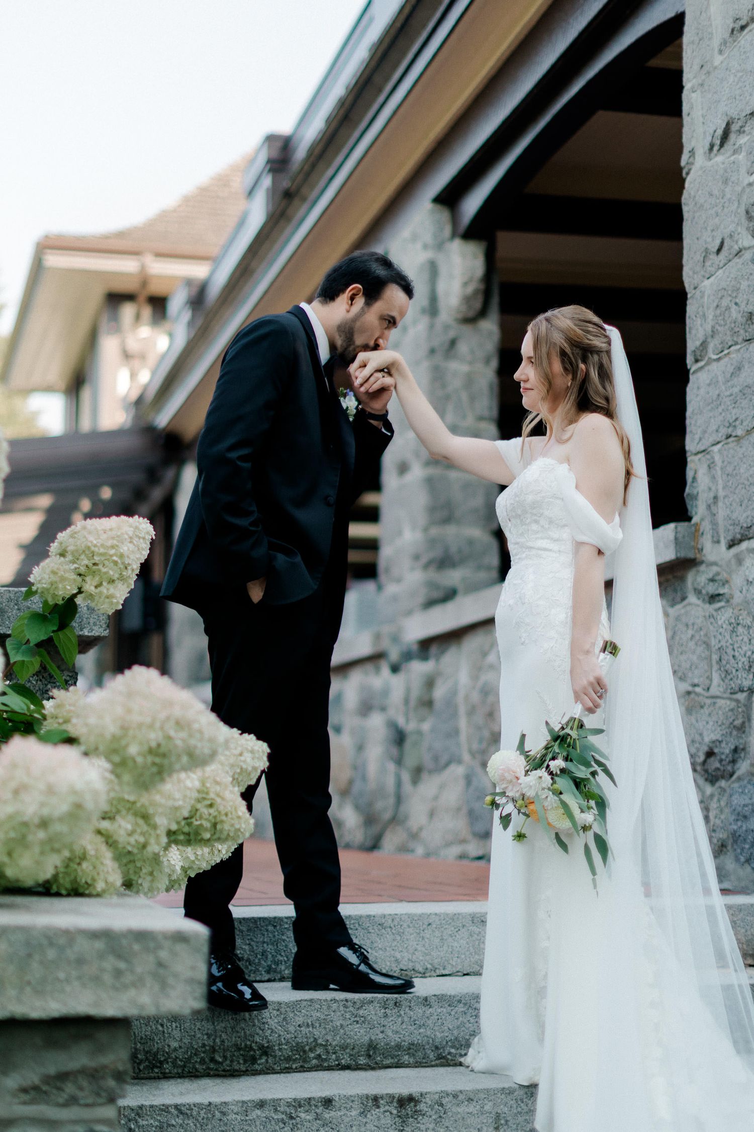 Romantic wedding couple poses on stone steps in a series of intimate moments at their outdoor venue.
