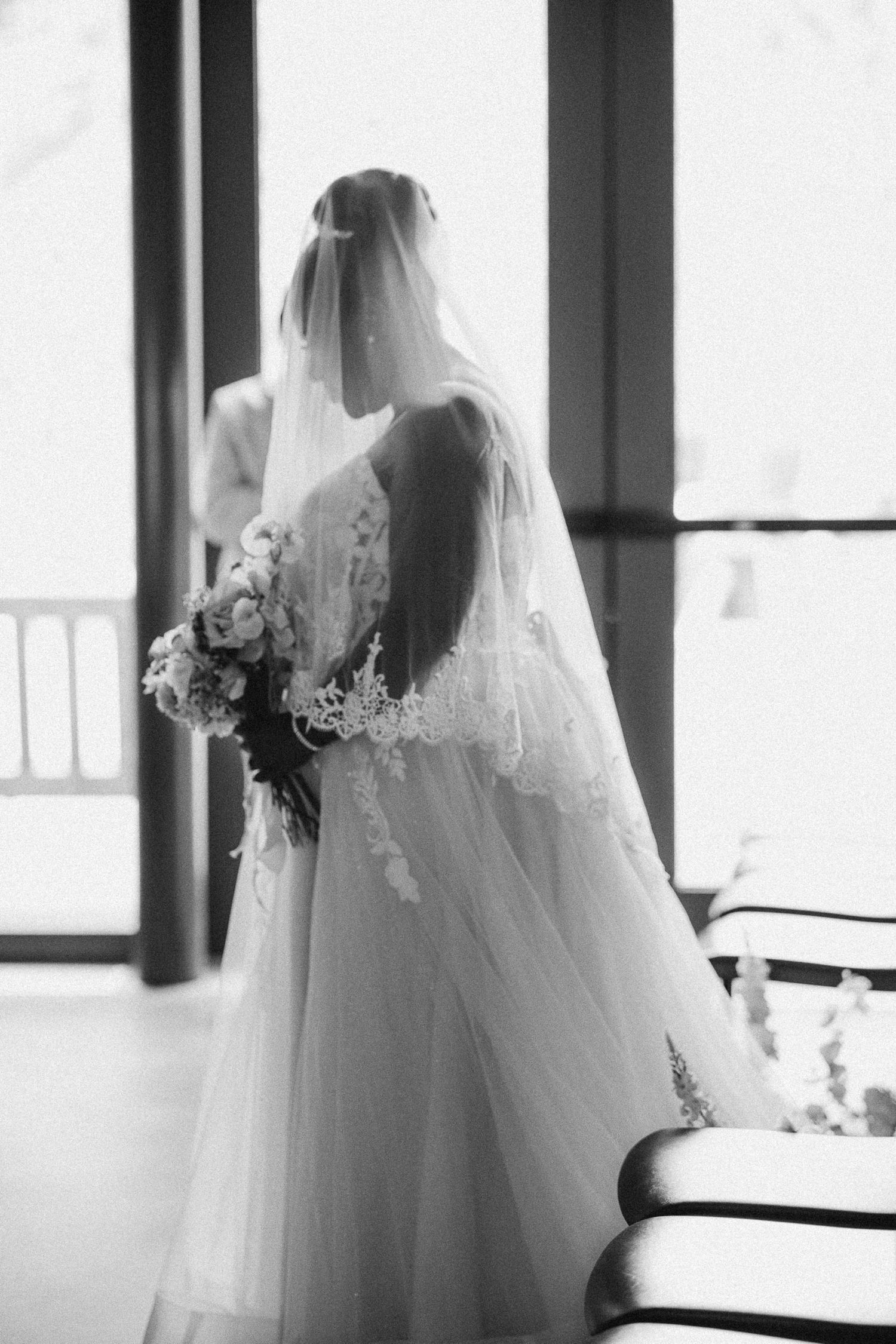 Ethereal black and white bridal portrait series showing flowing veil and wedding dress silhouettes by a window.