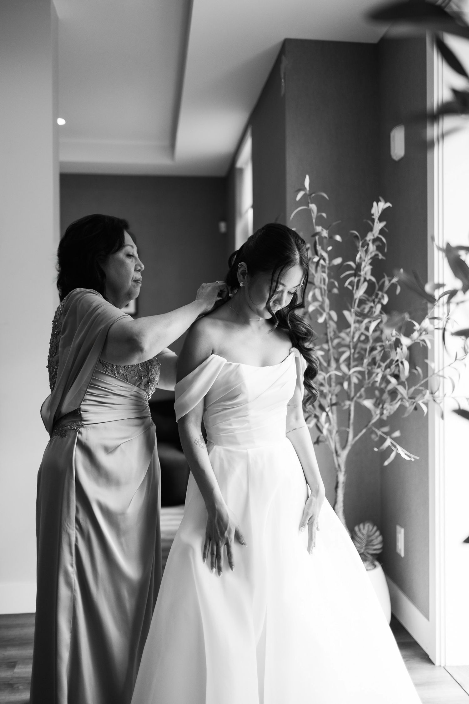 Mother helping bride with hair in black and white wedding preparation photo.