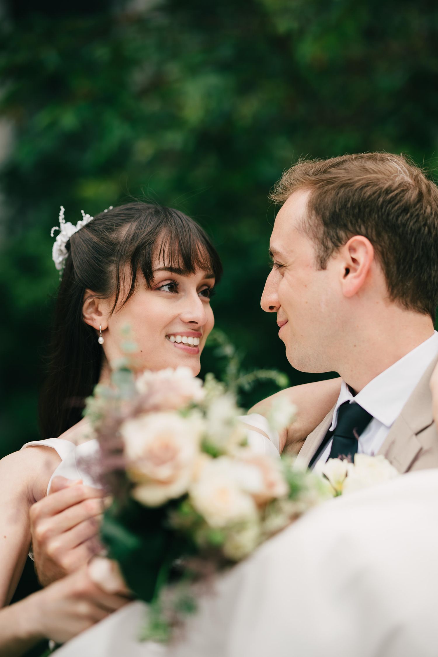 A romantic wedding photo series showing a couple gazing at each other with delicate pink flowers in the foreground.