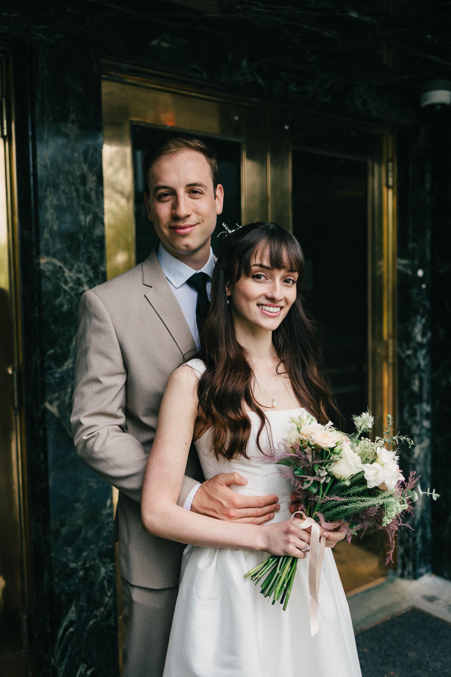 A couple shares a joyful moment together at their wedding, with the bride holding a white floral bouquet.