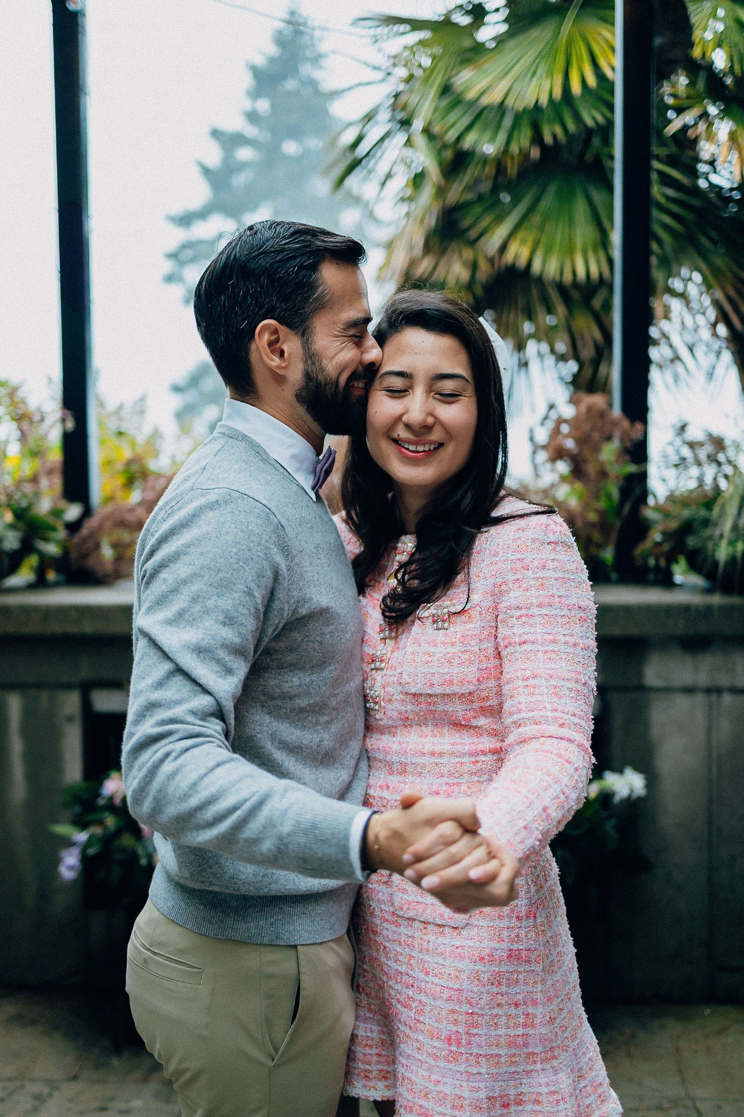 A couple shares intimate moments outdoors, with palm trees and greenery in the background.