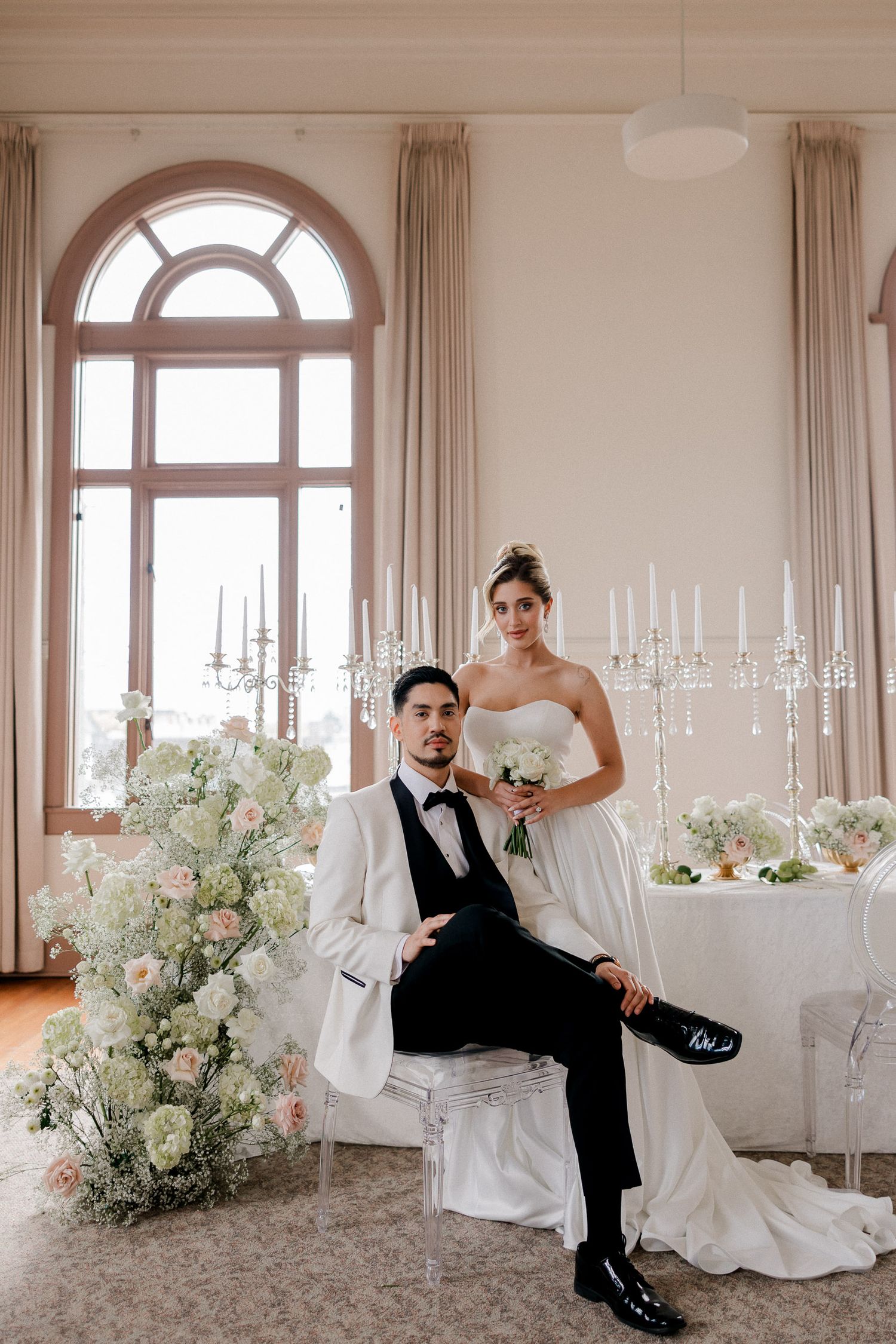 Elegant wedding venue with arched windows, white floral arrangements and romantic candlelit table settings.
