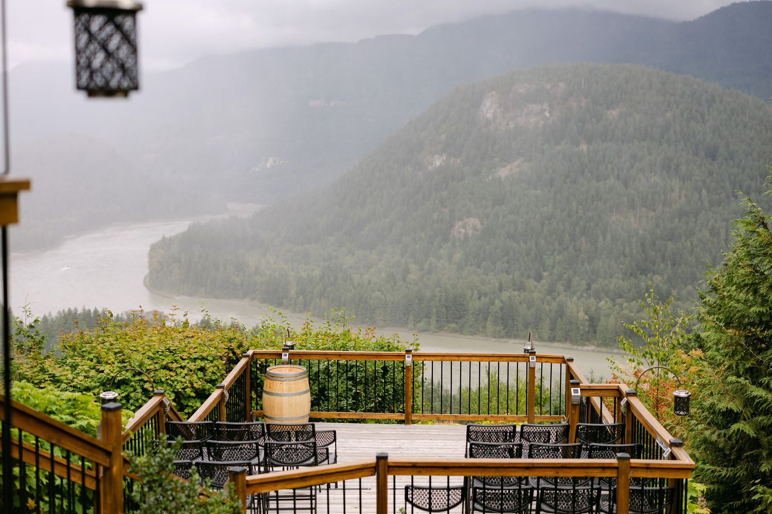 Wooden deck overlooking a misty mountain valley with a river and lush green forests in the Pacific Northwest.