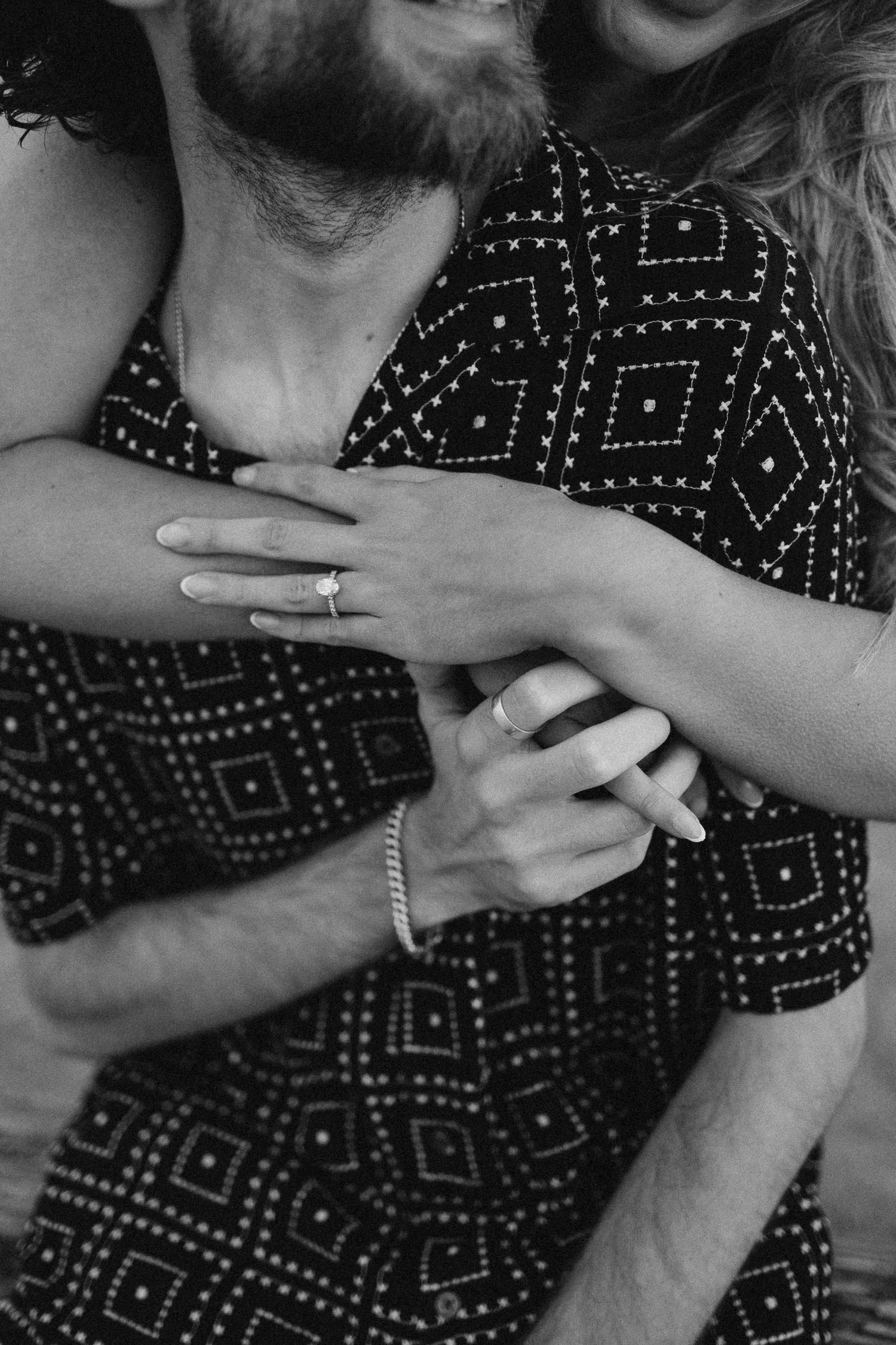 Close-up shots of hands with engagement rings in black and white against a patterned dress.