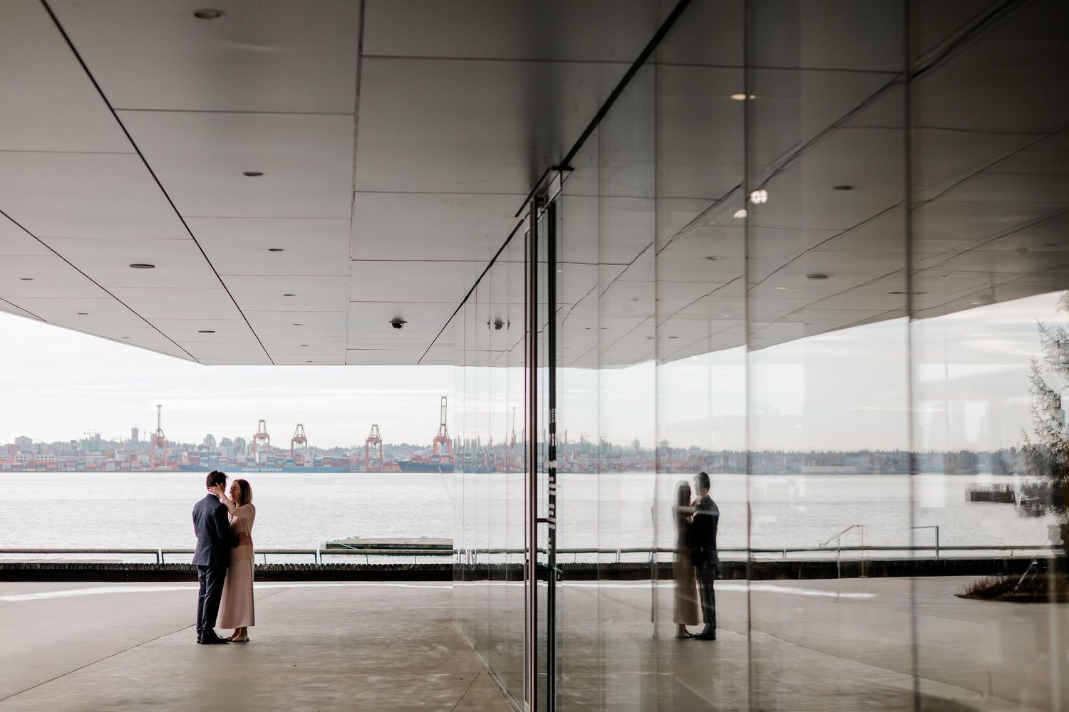 A modern architectural space with glass walls and a minimalist interior design showcases a panoramic city skyline view.