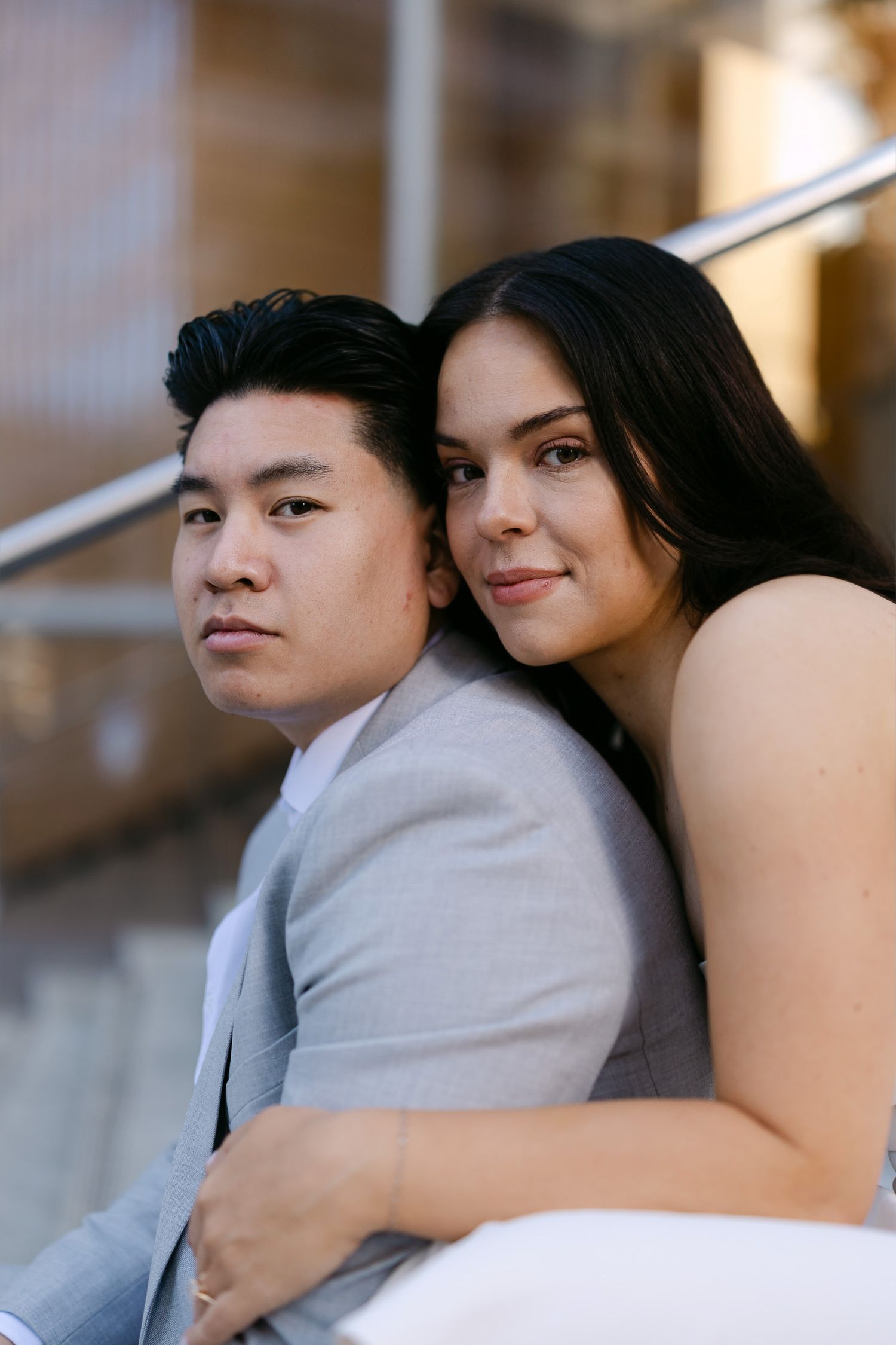 Close portrait of a woman in white embracing a man in a gray suit from behind during an engagement session.