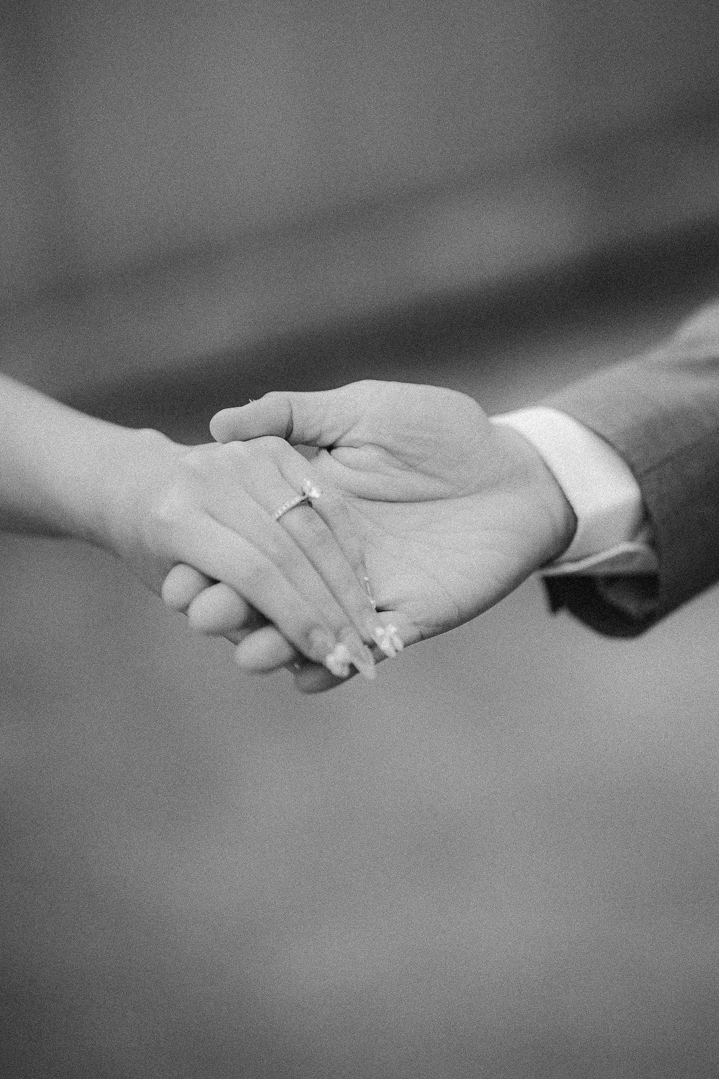 A sequence of black and white photographs showing two hands gently letting go of each other in a gradual release.
