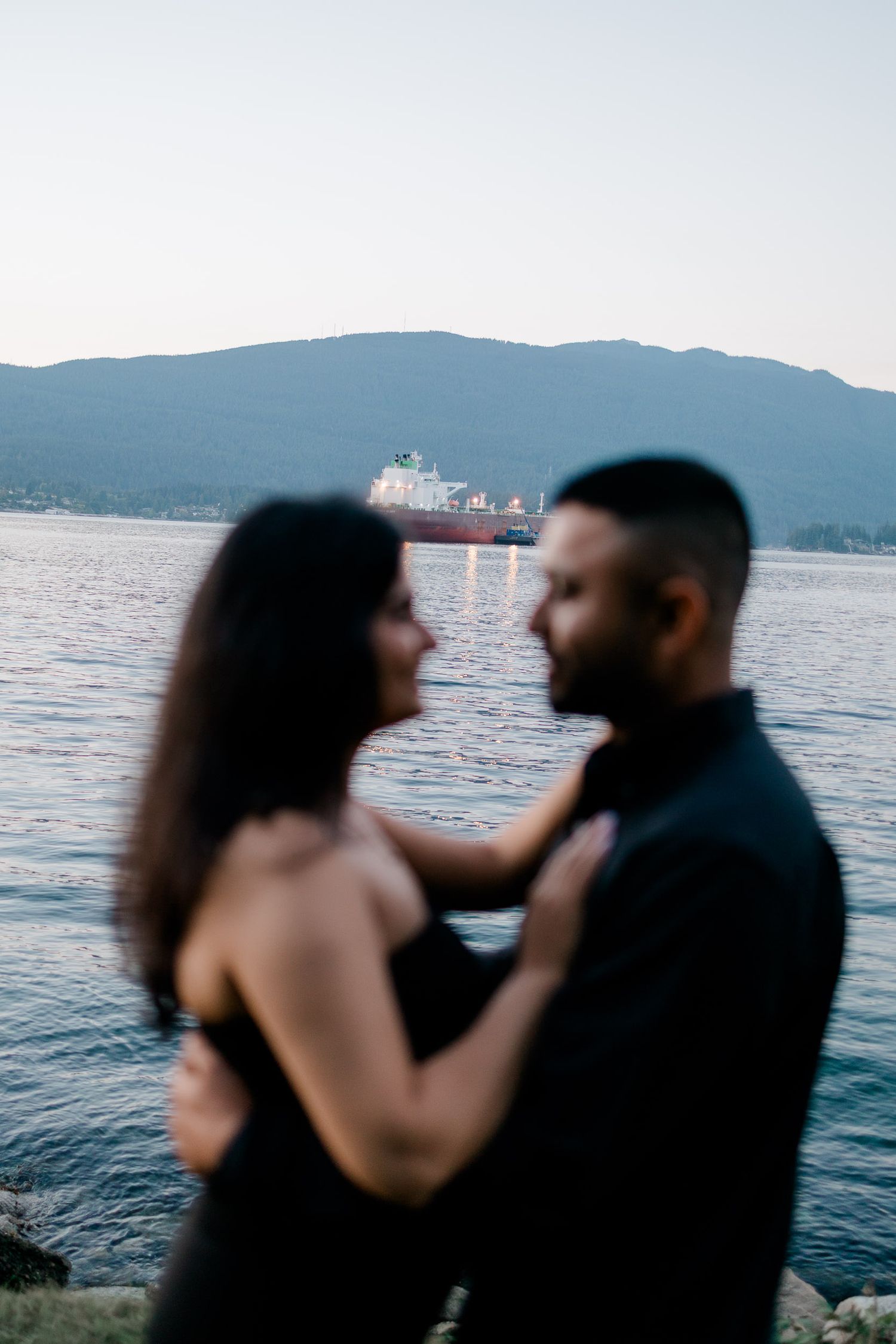 A romantic silhouette of a couple embracing against a scenic mountain lake backdrop at sunset.