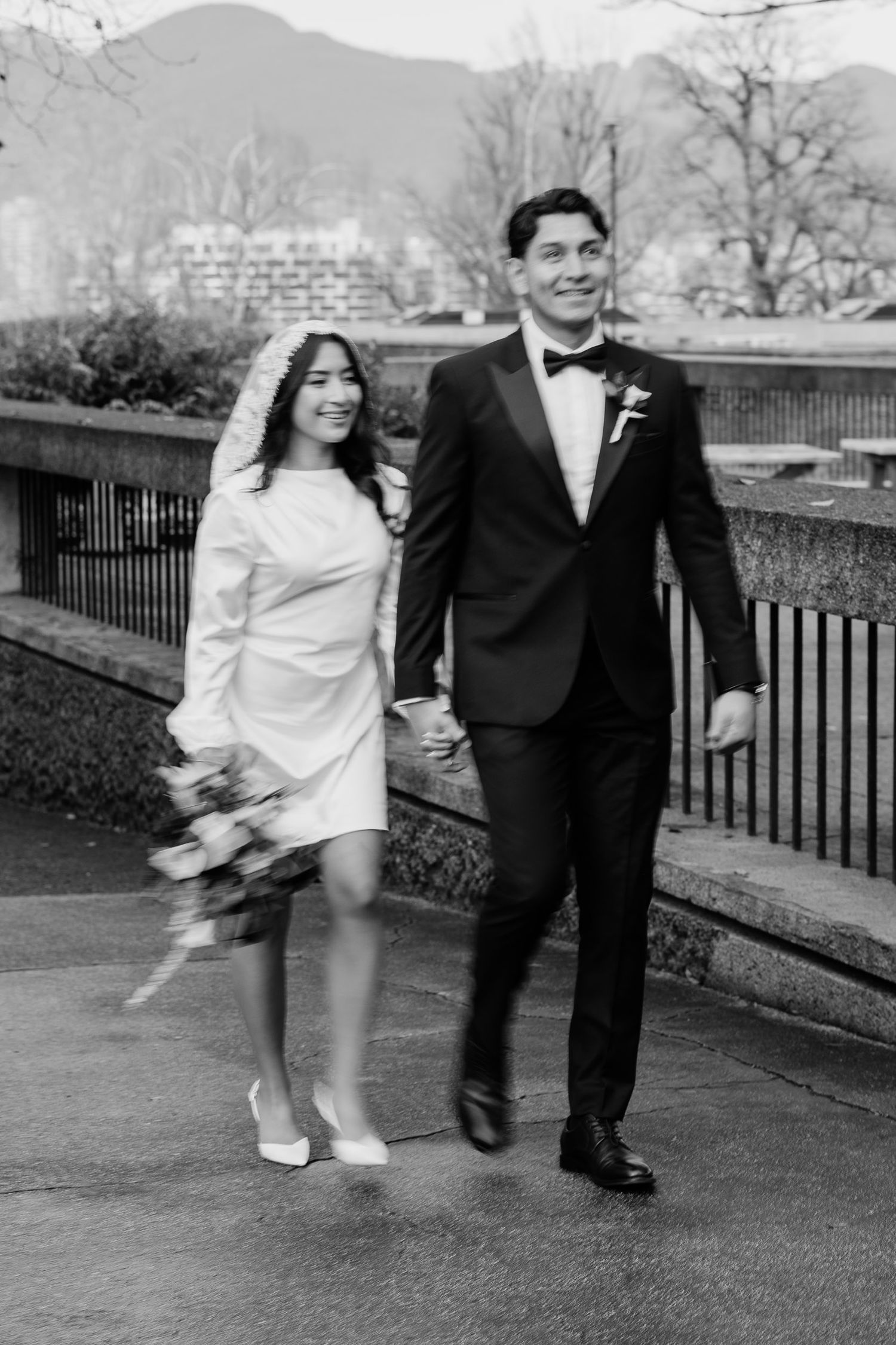 Vintage black and white wedding photo showing a couple walking outdoors with mountains in the background.