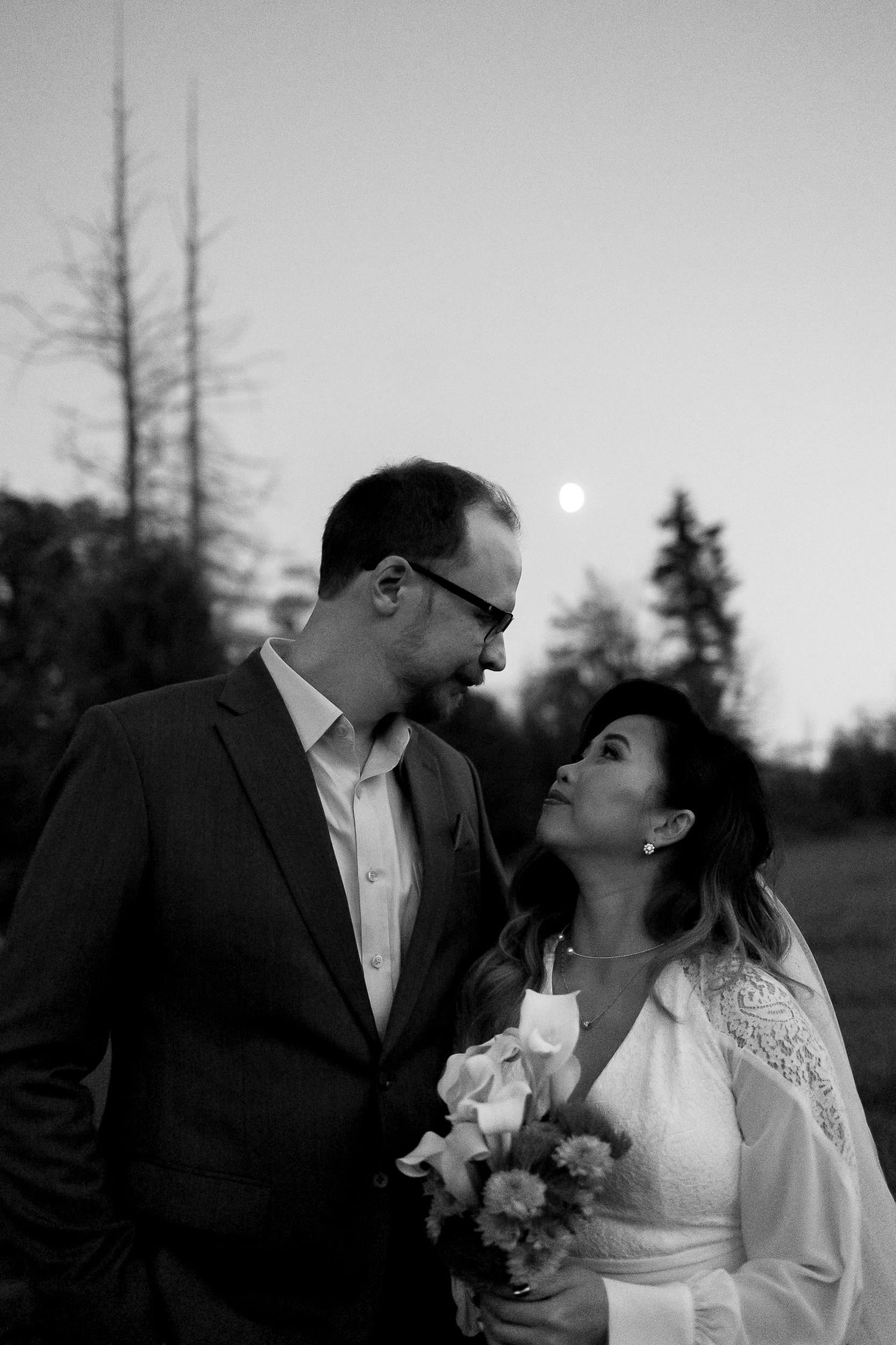 A romantic black and white photo series of a couple sharing intimate moments during their outdoor wedding celebration.
