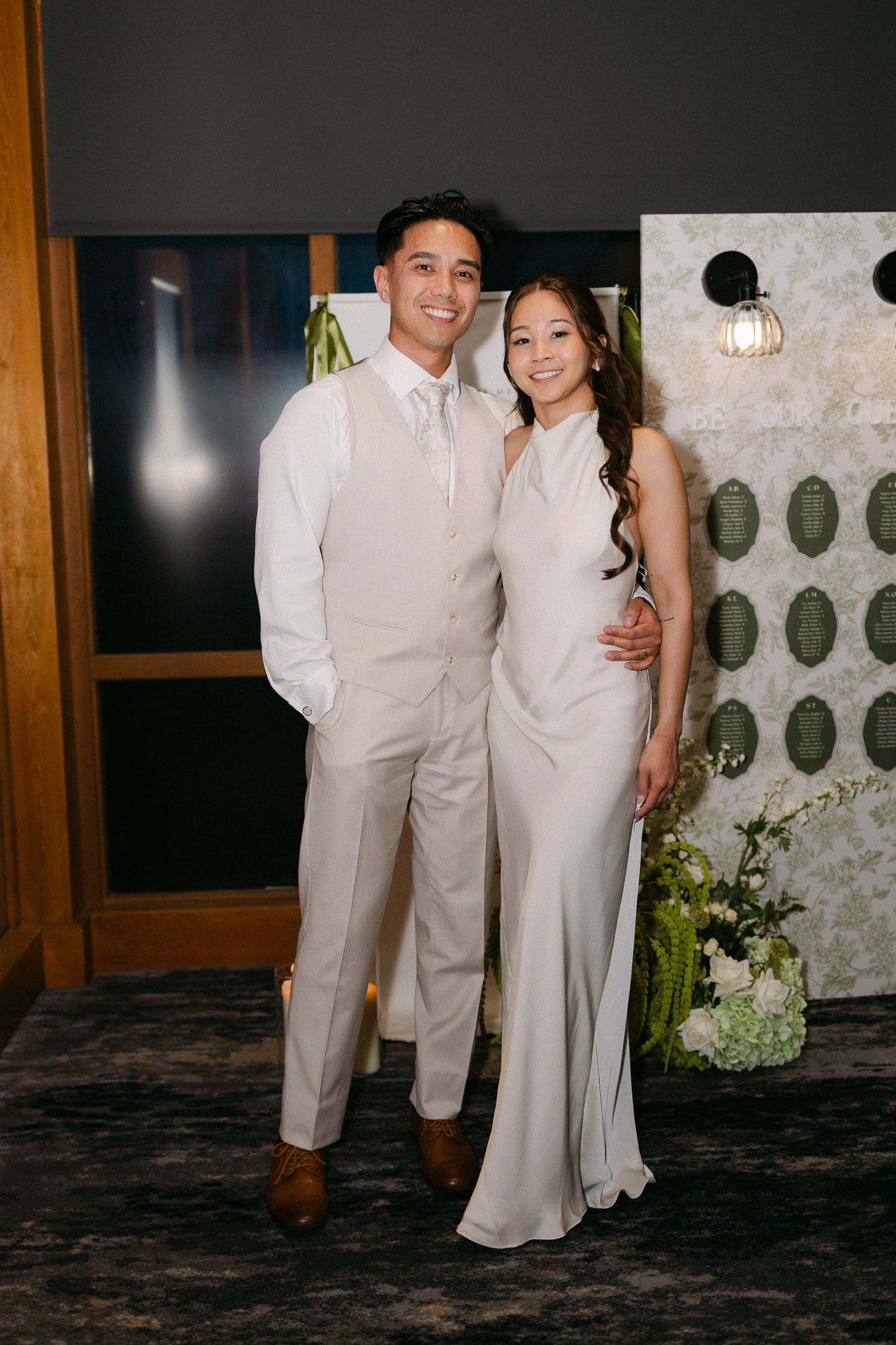 Couple posing together in elegant neutral wedding attire at a formal event venue.
