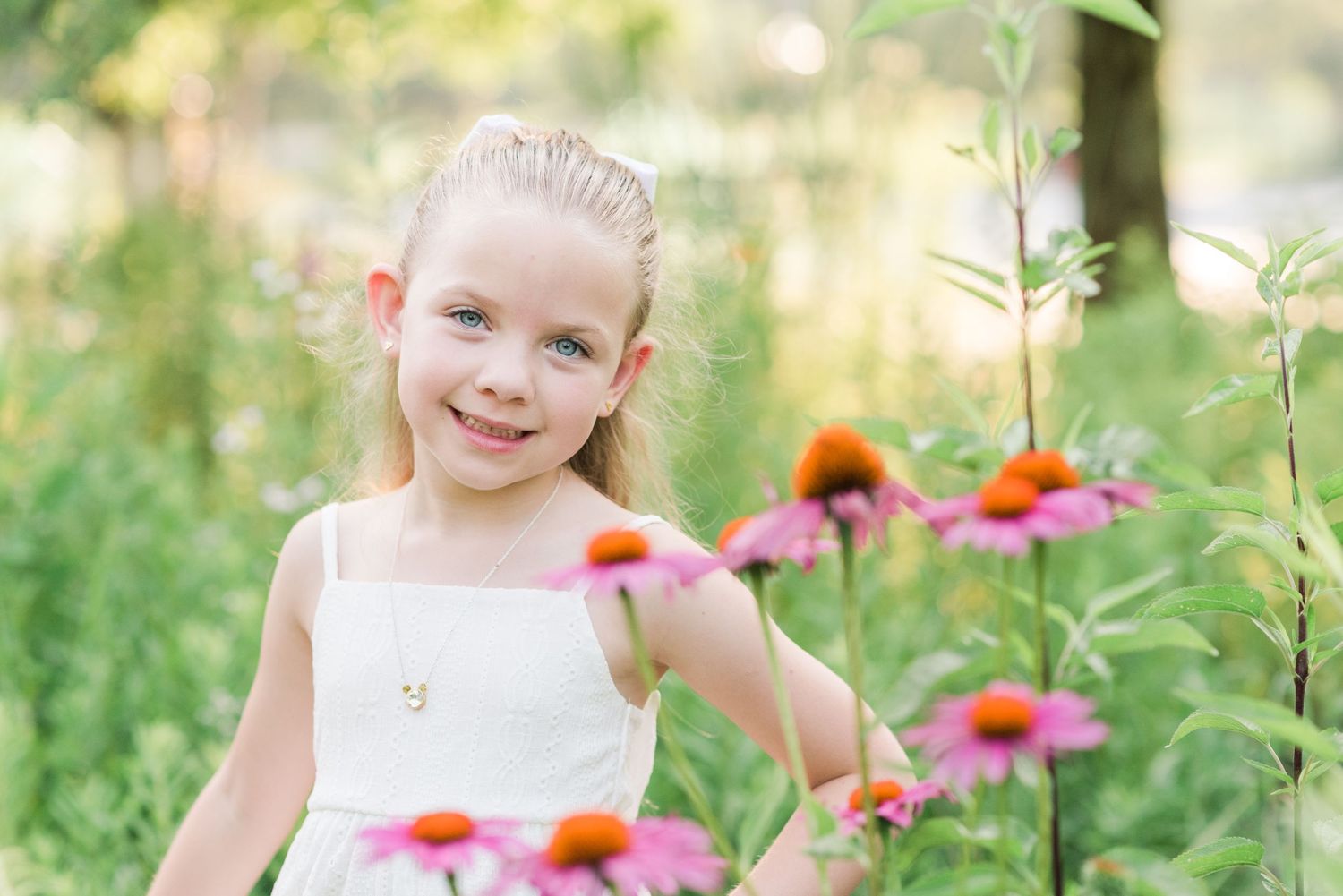 A white summer dress among vibrant pink and orange wildflowers in a sunny garden setting.