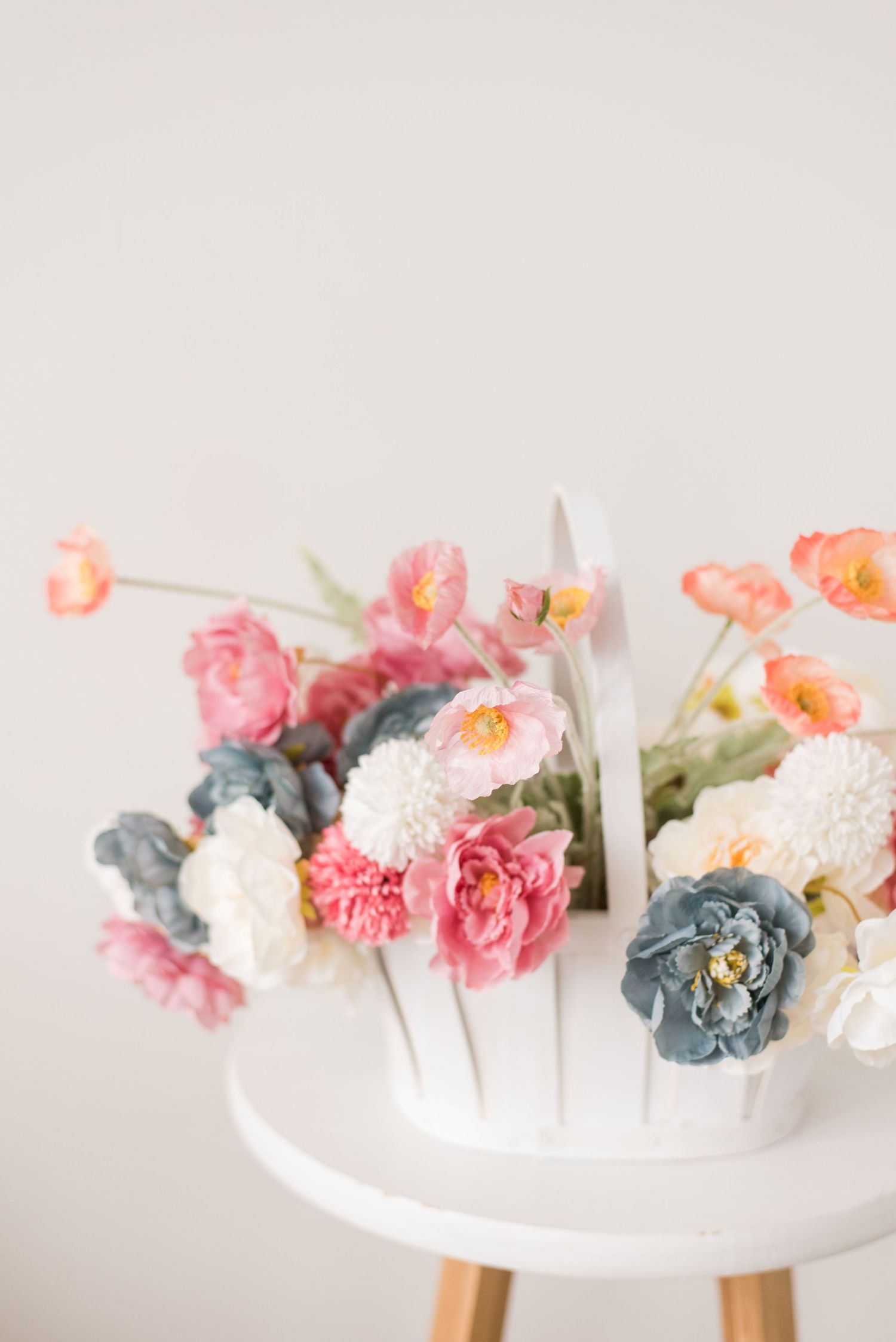 A floral crown made with white, pink, and blue paper flowers arranged in a circle against a light background.