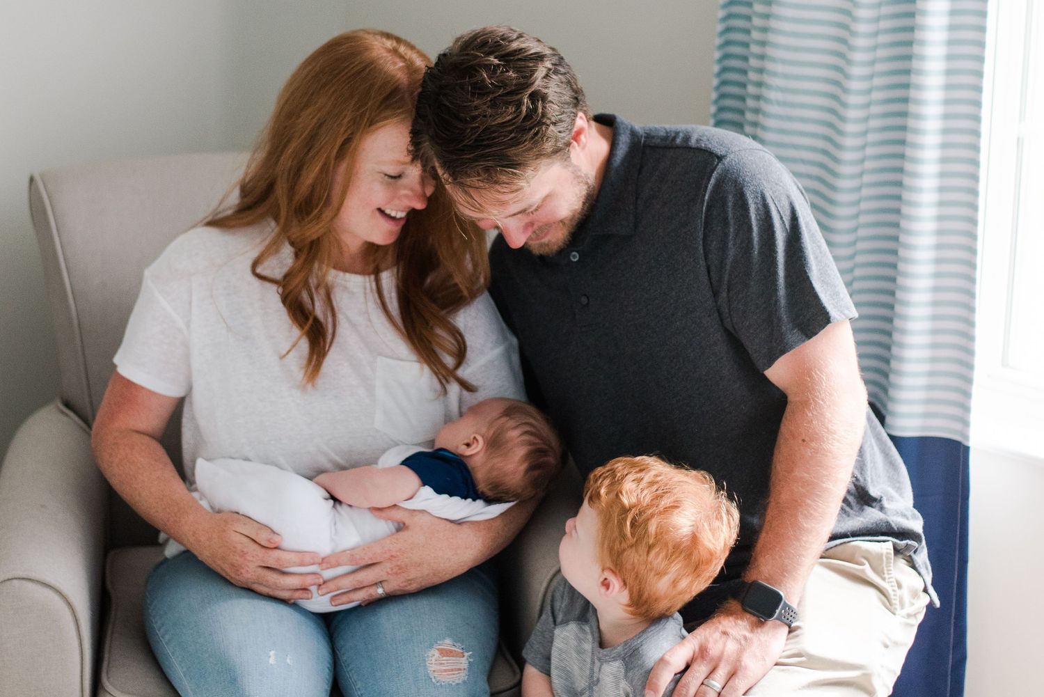 A tender family moment captured in soft lighting on a comfortable gray couch.
