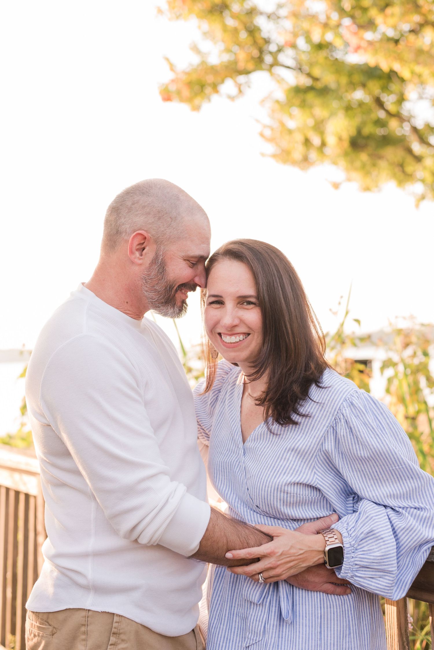 A couple shares tender moments outdoors in matching white and blue striped outfits during a golden sunset.