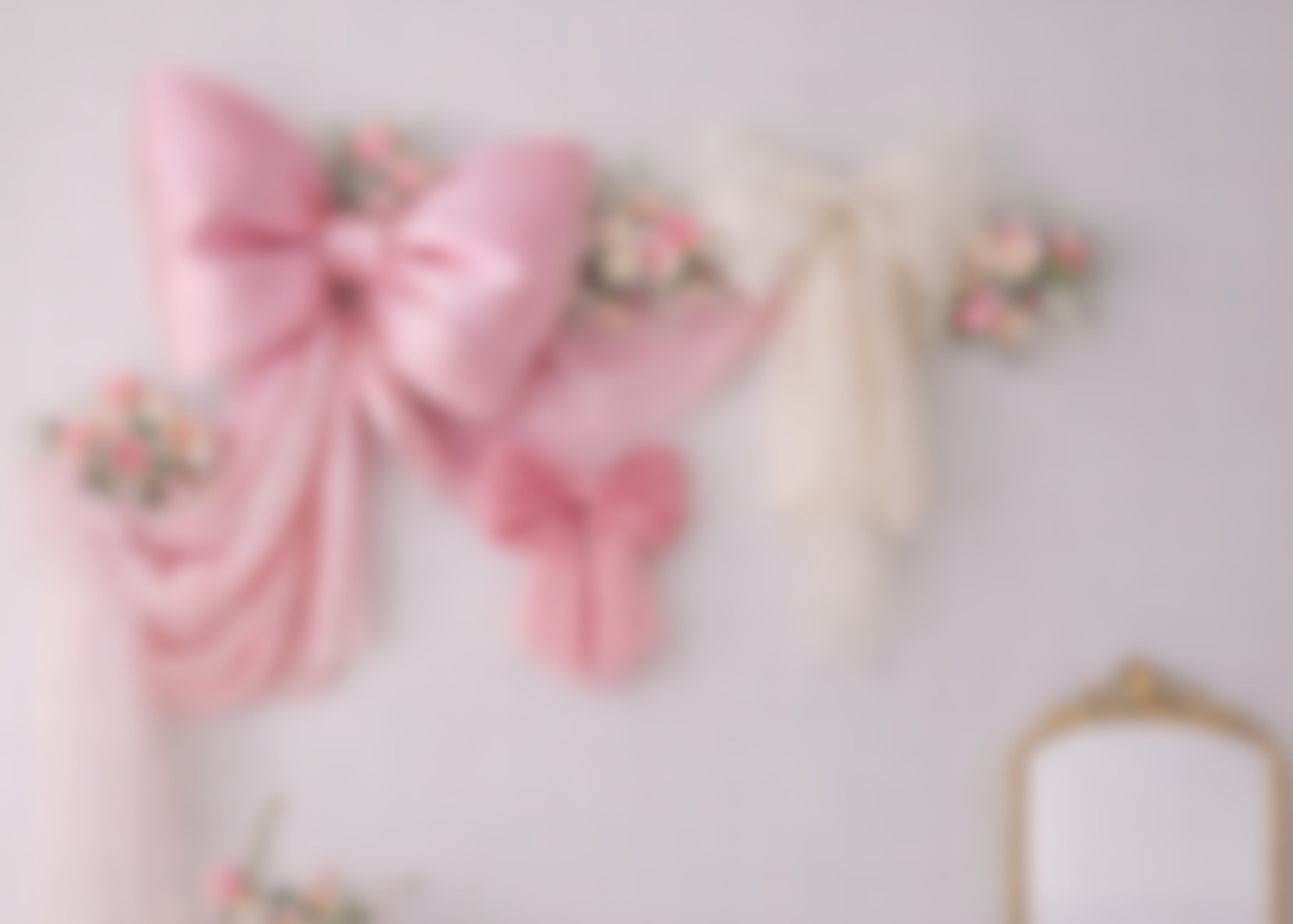 Pink fabric bows and delicate floral decorations arranged on a white surface create a romantic, feminine composition.