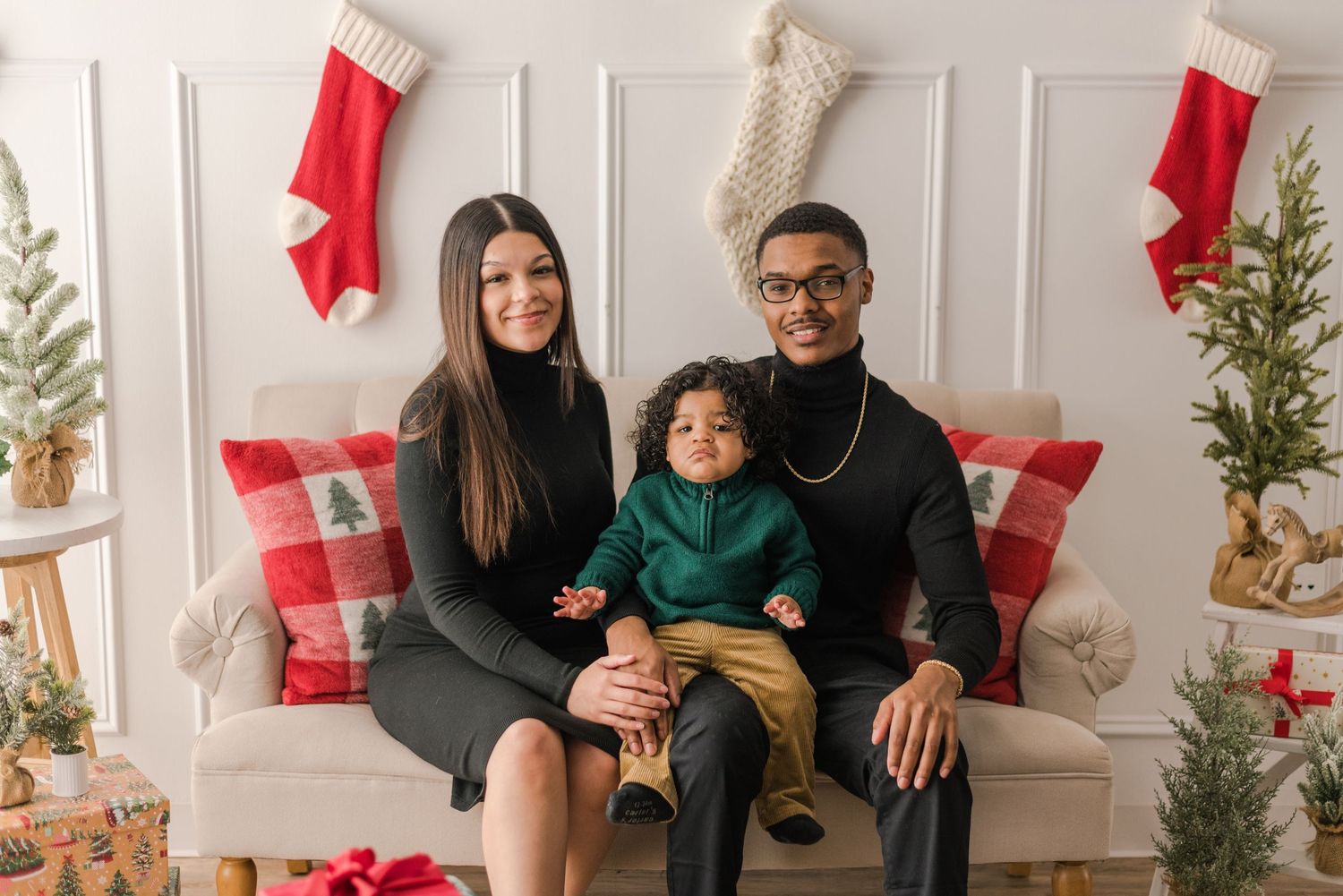 A family wearing festive red and green clothing poses for holiday photos in front of a white wall with Canadian flags.