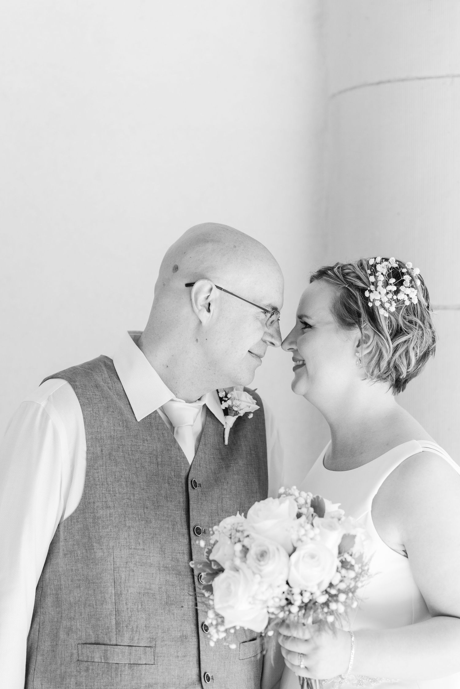 A tender black and white wedding portrait showing the couple sharing an intimate moment with a bouquet.
