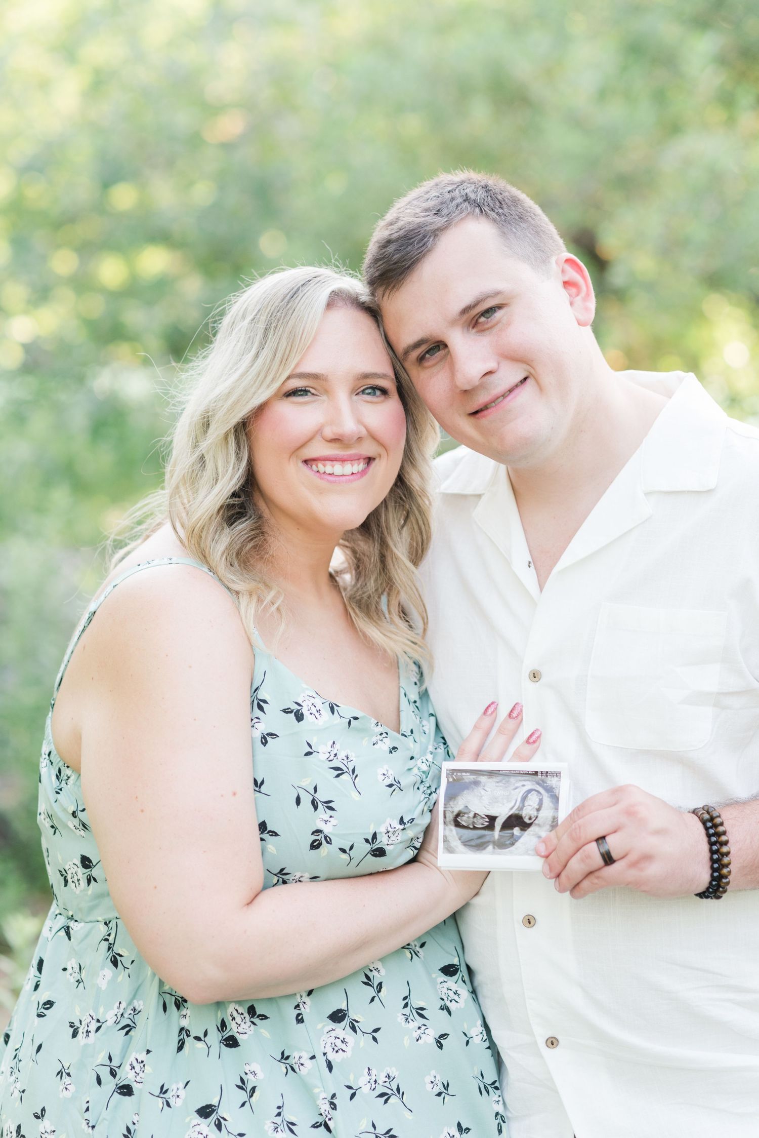 A happy couple poses together outdoors while sharing sweet moments in matching white and mint green outfits.