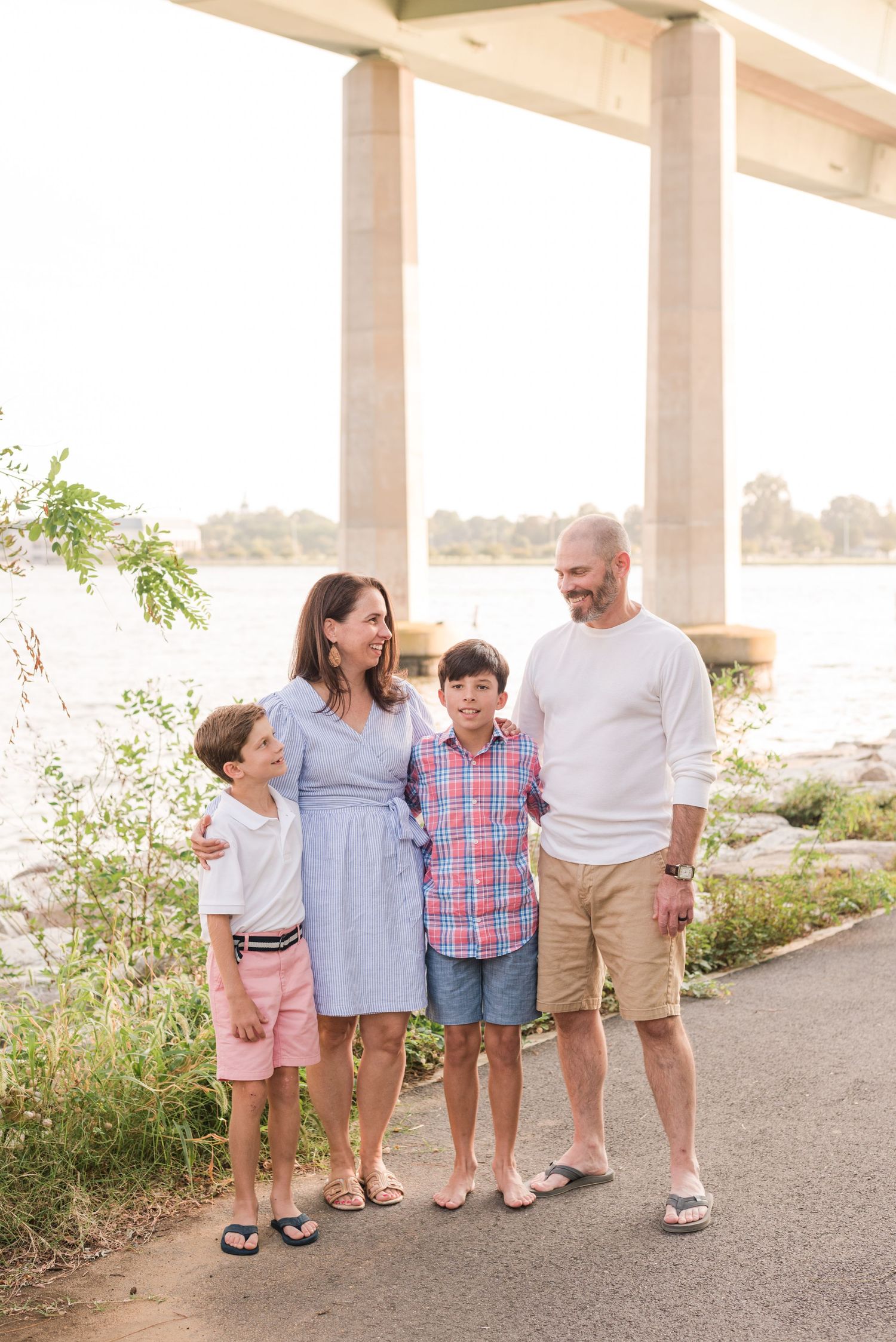 Family walking together on a waterfront path during a summer sunset photoshoot.